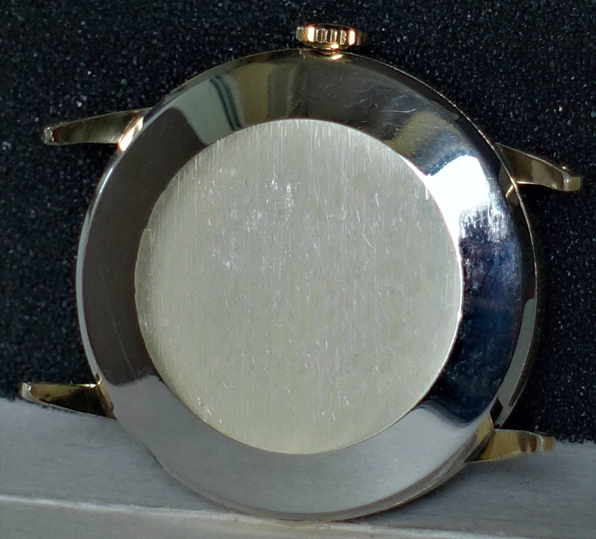 Rundes silberfarbenes Uhrgehäuse mit Krone und vier Bandanstößen, Rückseite sichtbar.