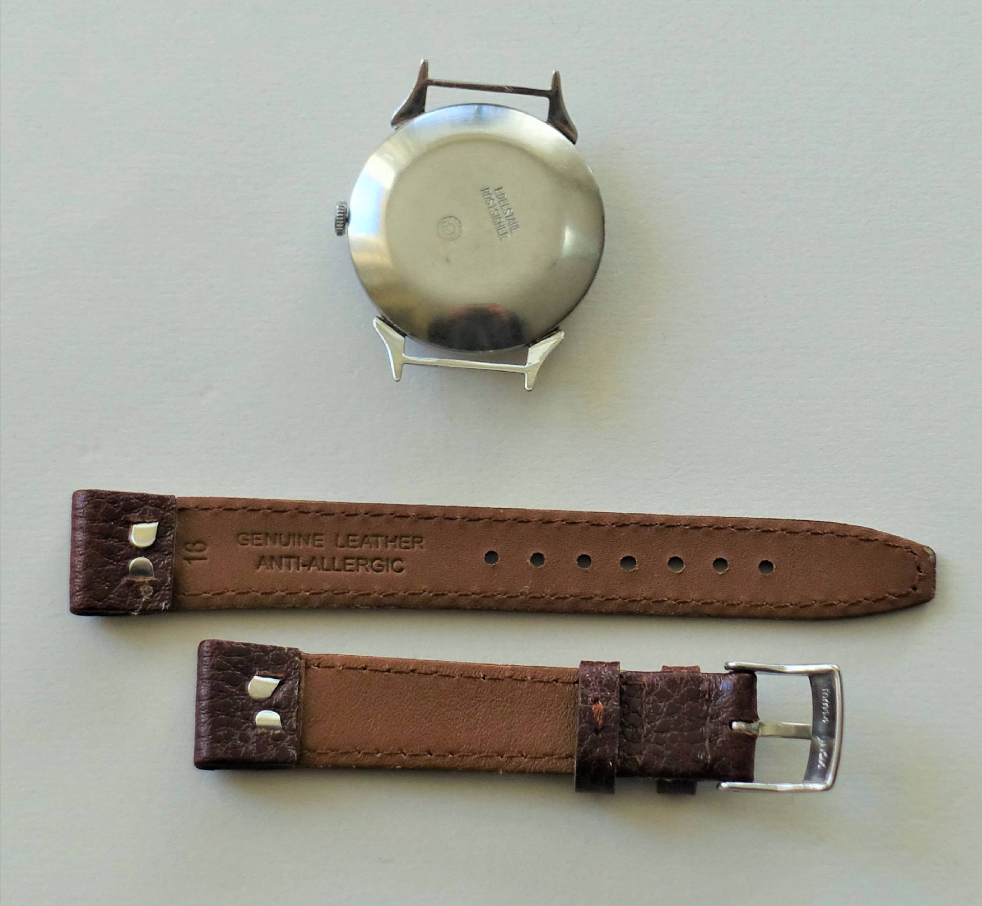 Silberfarbenes Uhrengehäuse mit braunem Lederarmband in zwei Teilen.