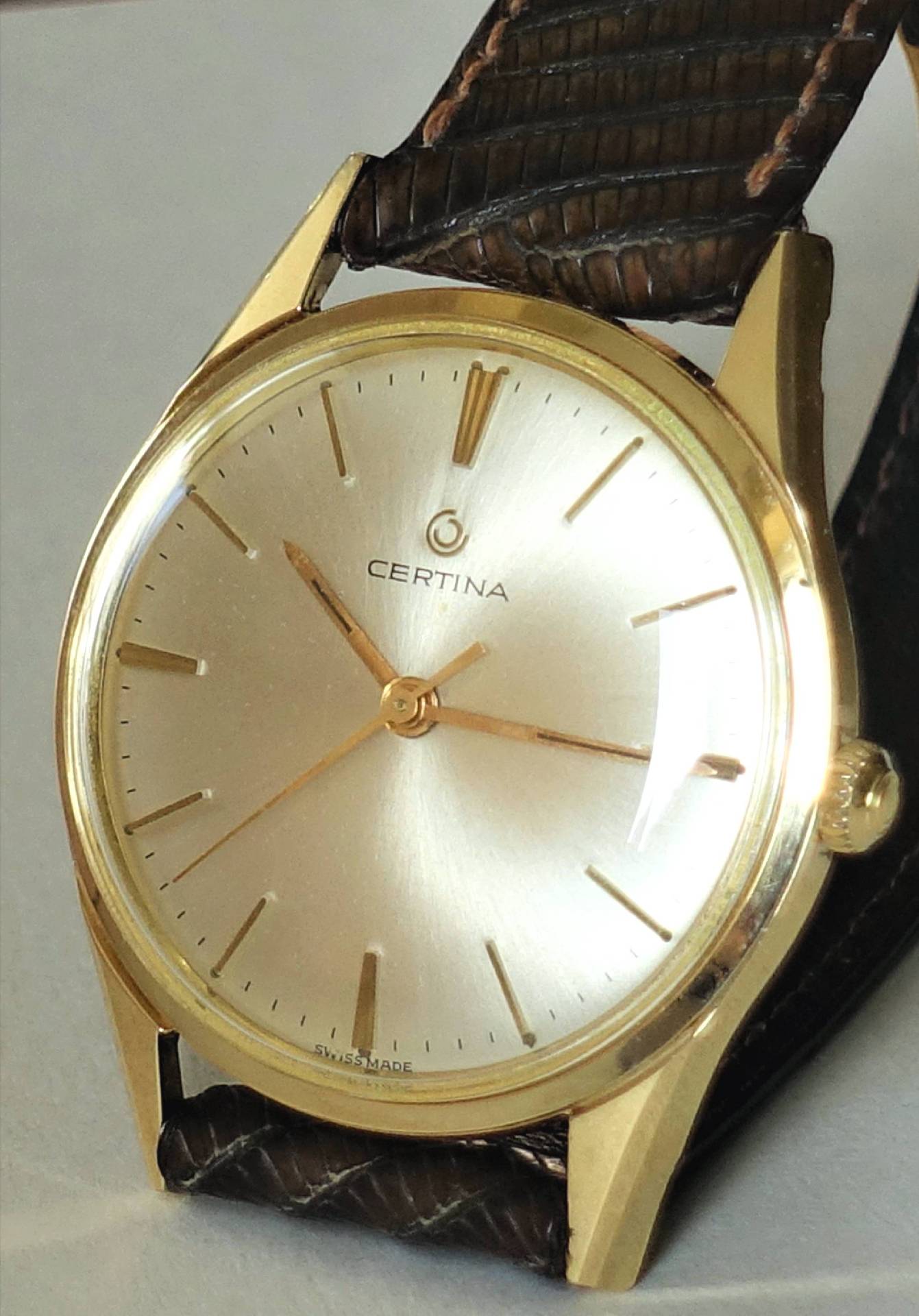 Goldfarbene Certina Armbanduhr mit hellem Zifferblatt und braunem Armband.