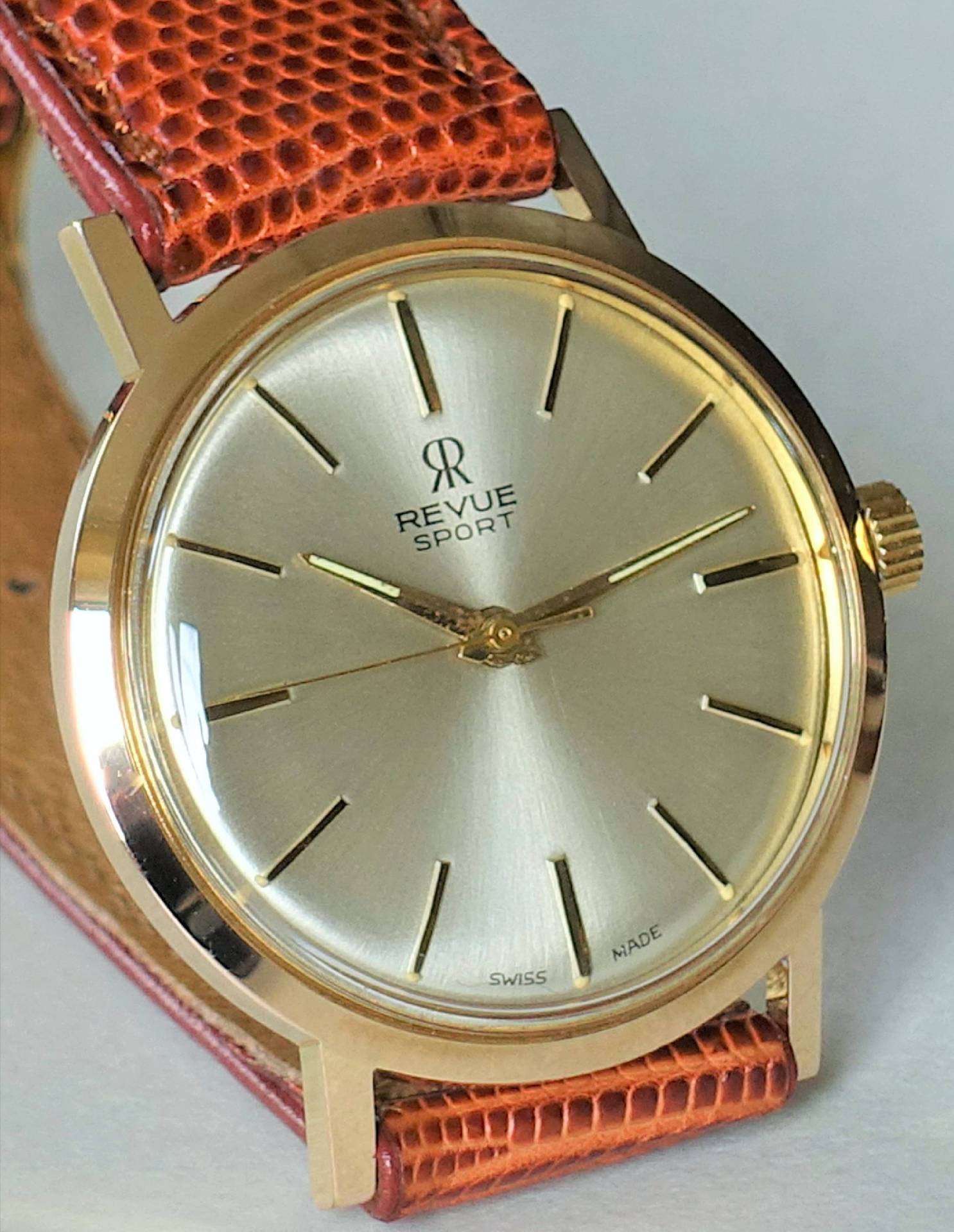 Goldfarbene Armbanduhr mit hellem Zifferblatt und braunem Lederarmband.