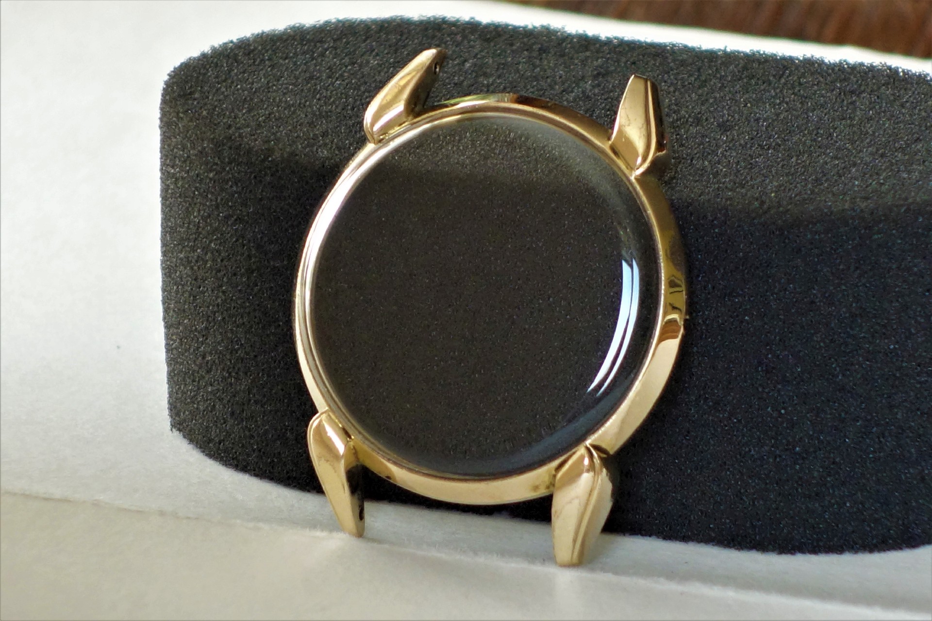 Rundes Uhrgehäuse in goldfarbener Ausführung mit montiertem Glas.