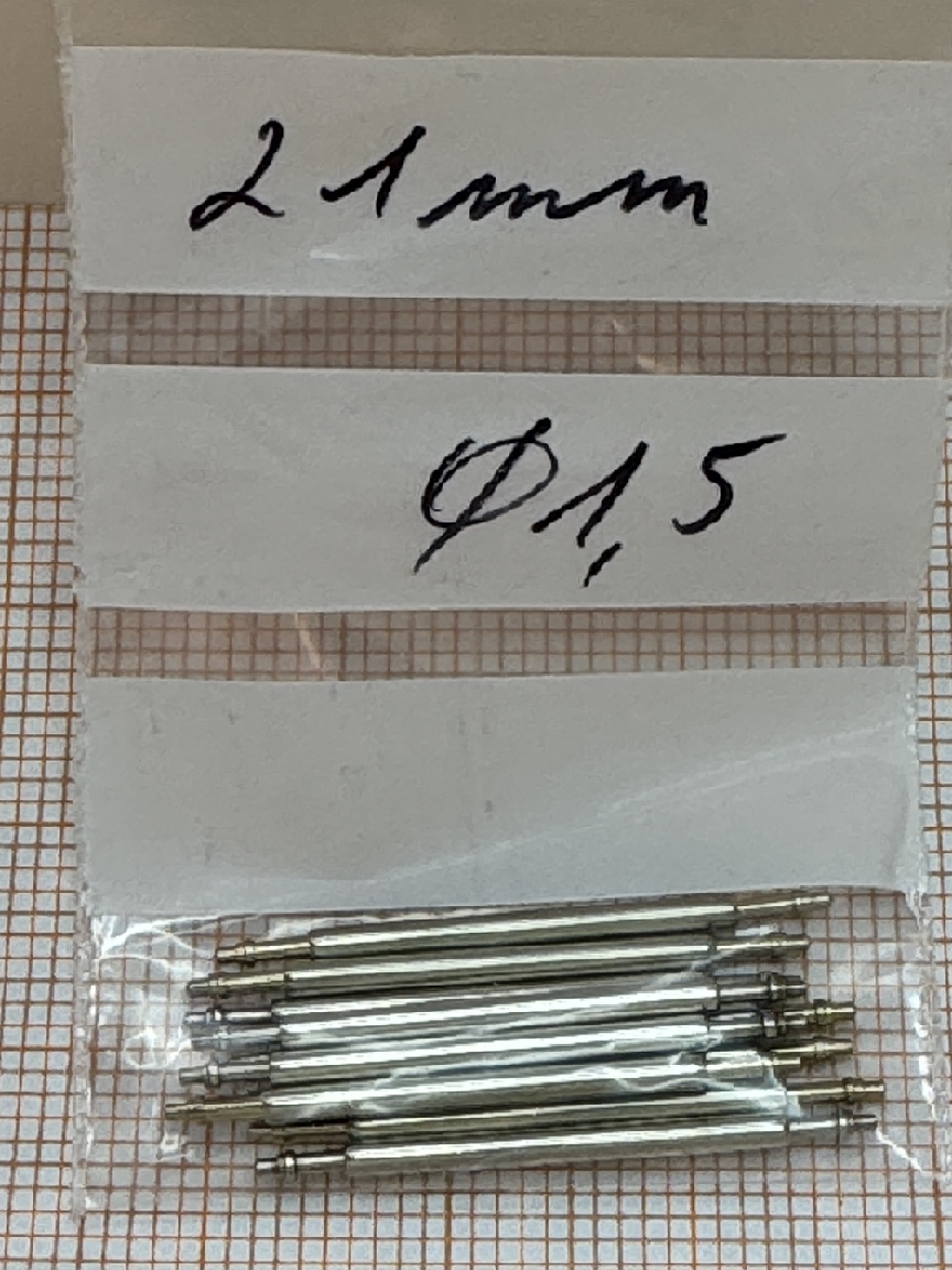 Mehrere silberfarbene Federstege aus Metall für Uhrenarmbänder in einem Plastikbeutel.