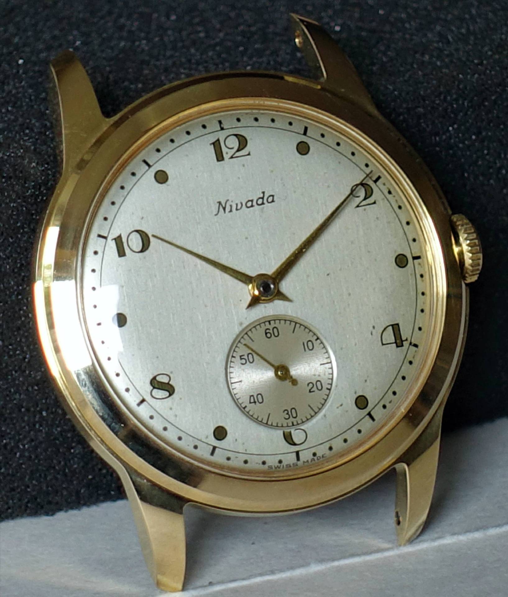 Goldfarbene Armbanduhr mit hellem Zifferblatt und kleiner Sekunde bei sechs Uhr.