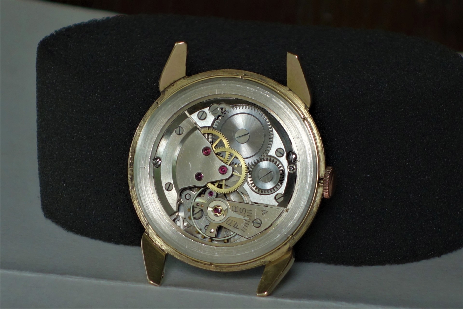 Mechanisches Uhrwerk in einem goldfarbenen Uhrengehäuse ohne Zifferblatt und Armband.