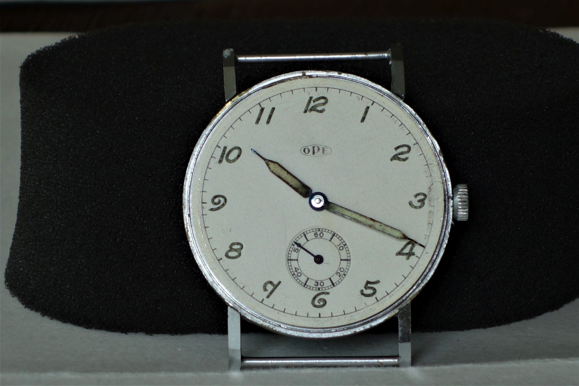 Runde silberfarbene Armbanduhr mit weißem Zifferblatt und kleiner Sekunde bei sechs Uhr.