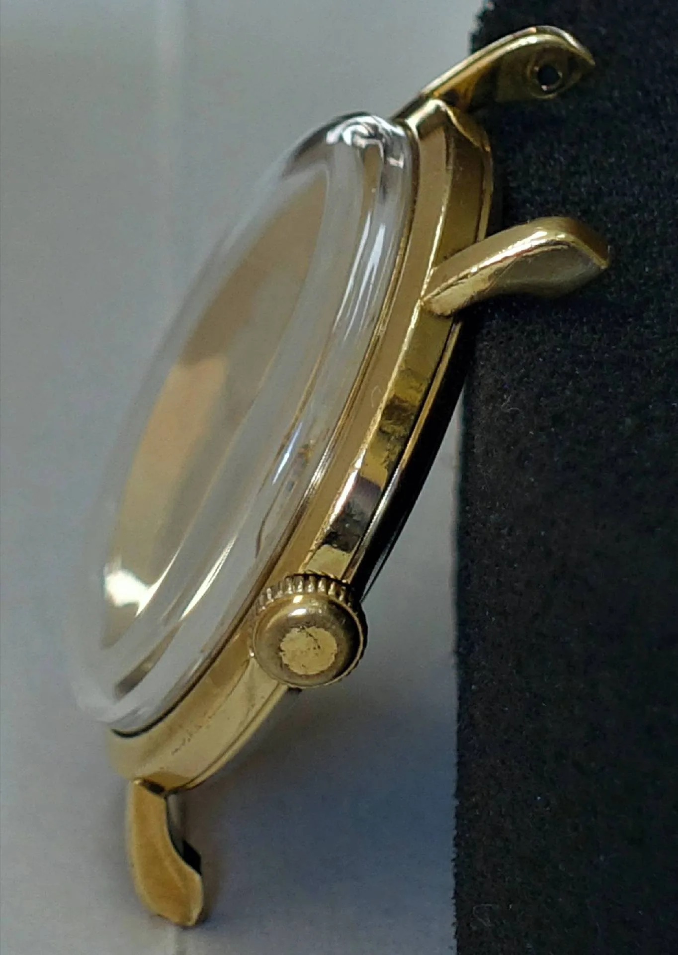 Uhrengehäuse goldfarben Goldfarbenes Uhrengehäuse mit Krone und transparentem Uhrglas.