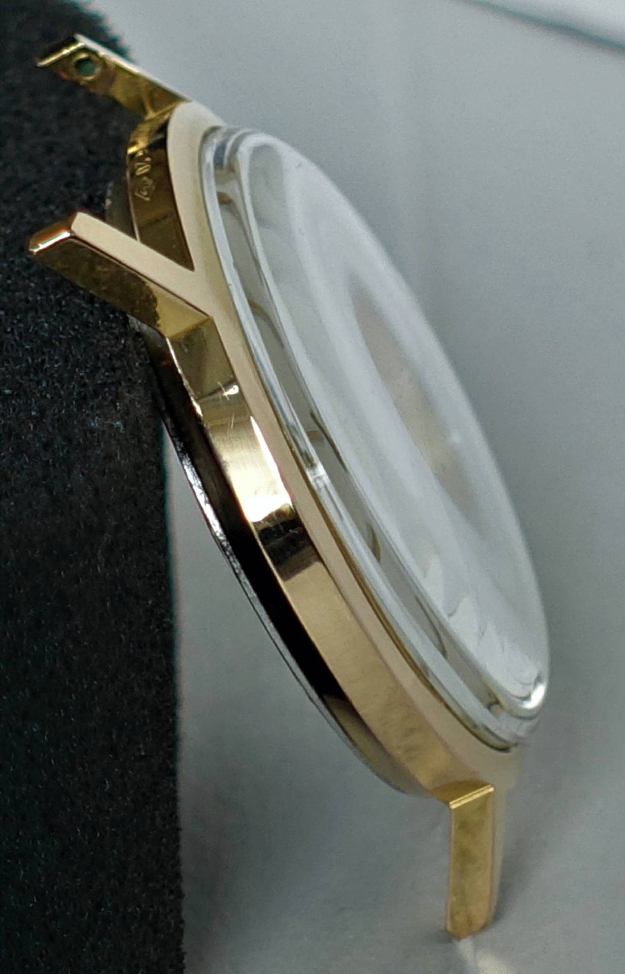 Goldfarbenes Uhrengehäuse mit montiertem Uhrglas.