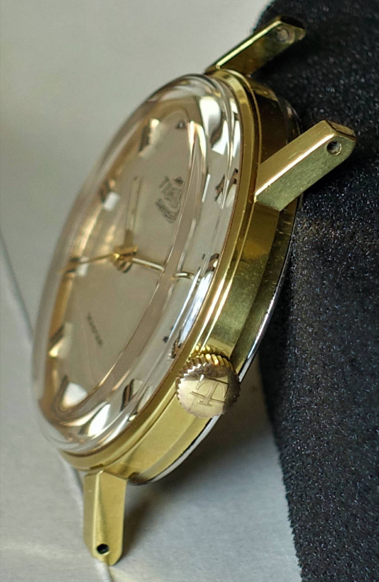 Goldfarbene Armbanduhr mit hellem Zifferblatt und seitlicher Krone.