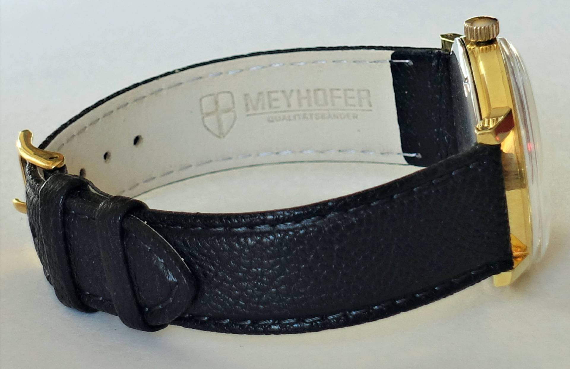 Schwarze Armbanduhr mit goldfarbenem Gehäuse und schwarzem Armband.