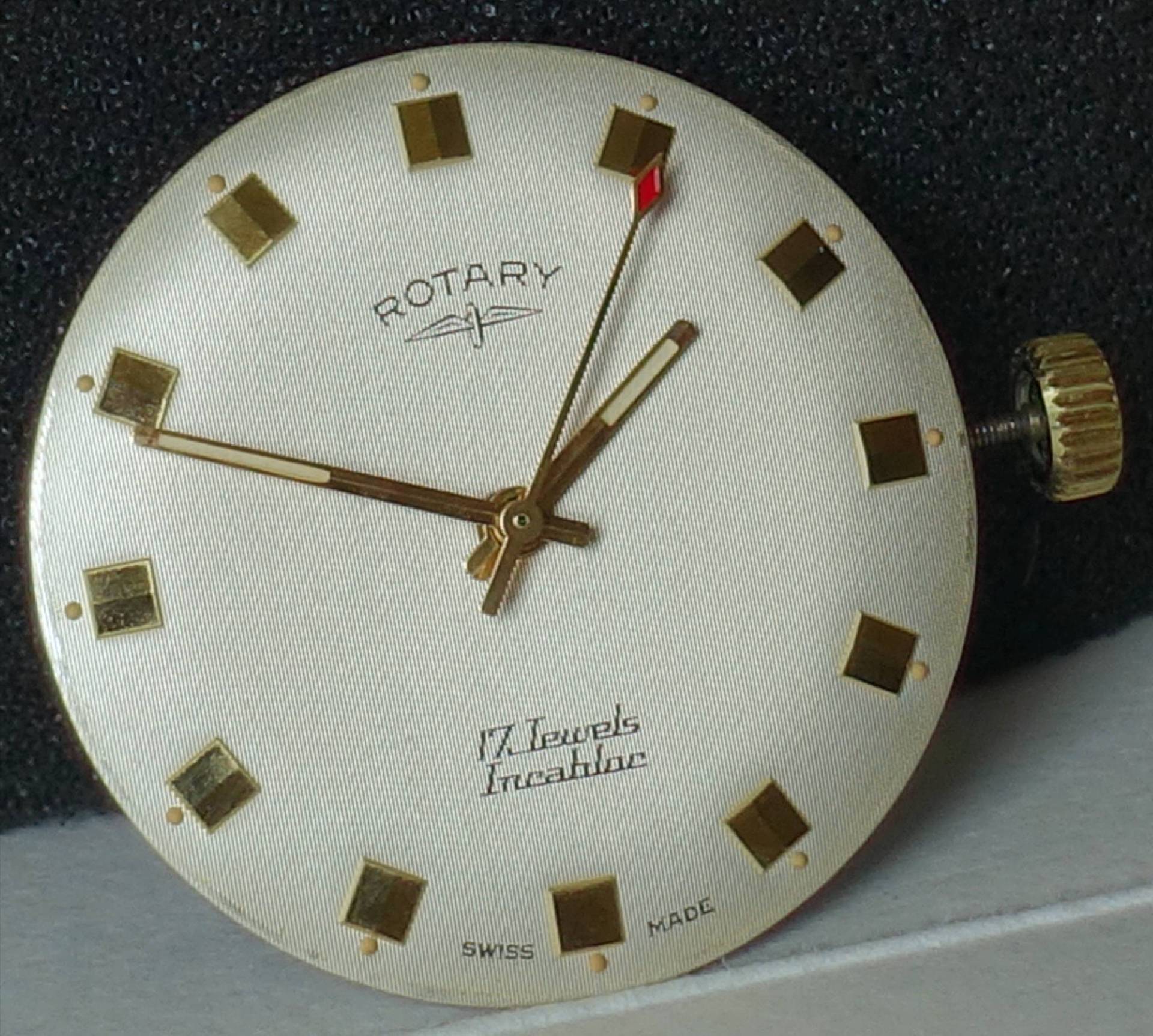Rundes Zifferblatt einer Vintage Rotary Armbanduhr mit goldenen Indizes, goldenen Zeigern und seitlicher Aufzugskrone.