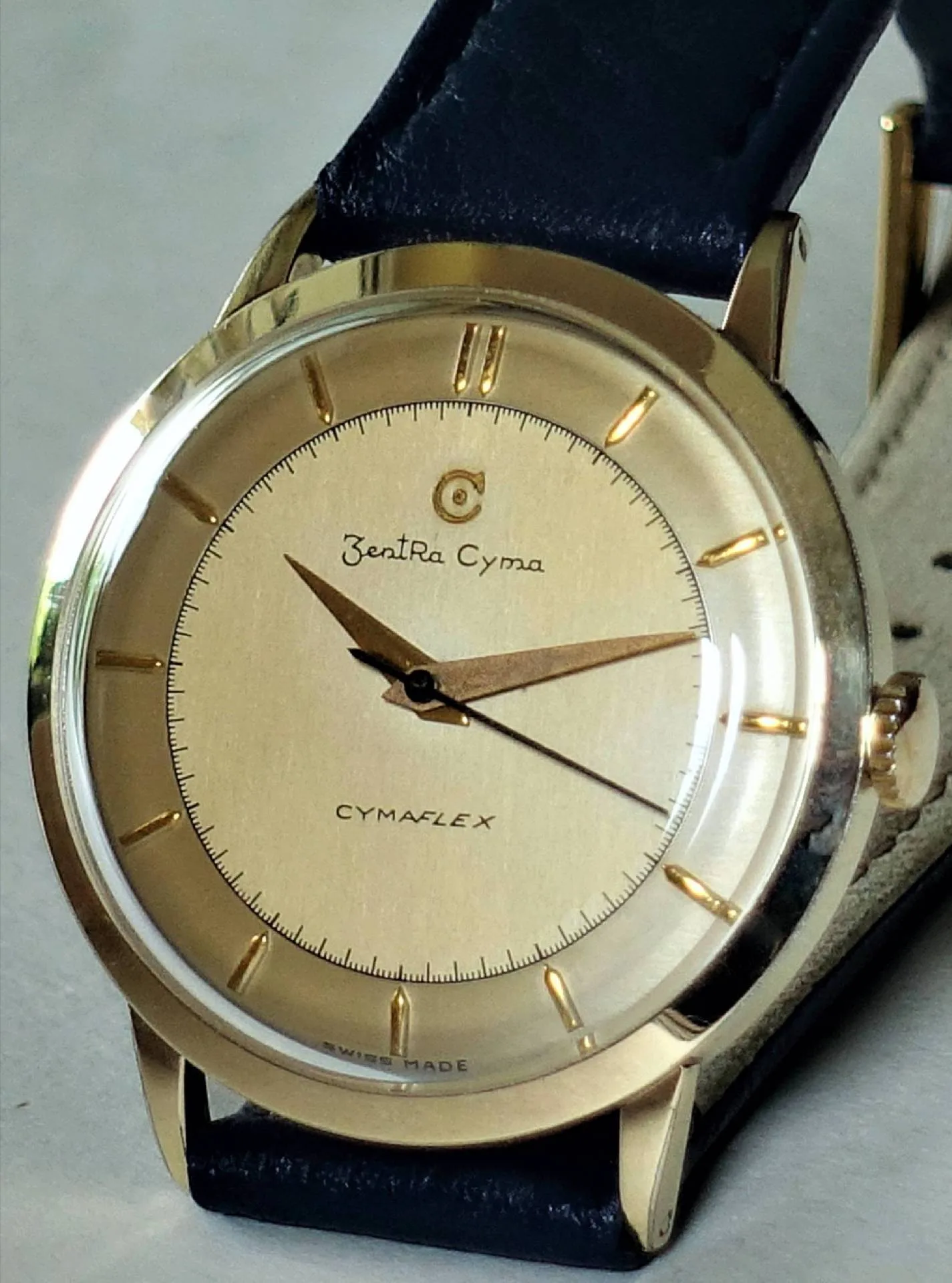 ZentRa Cyma Armbanduhr Goldfarbene Armbanduhr mit hellem Zifferblatt und schwarzem Armband.