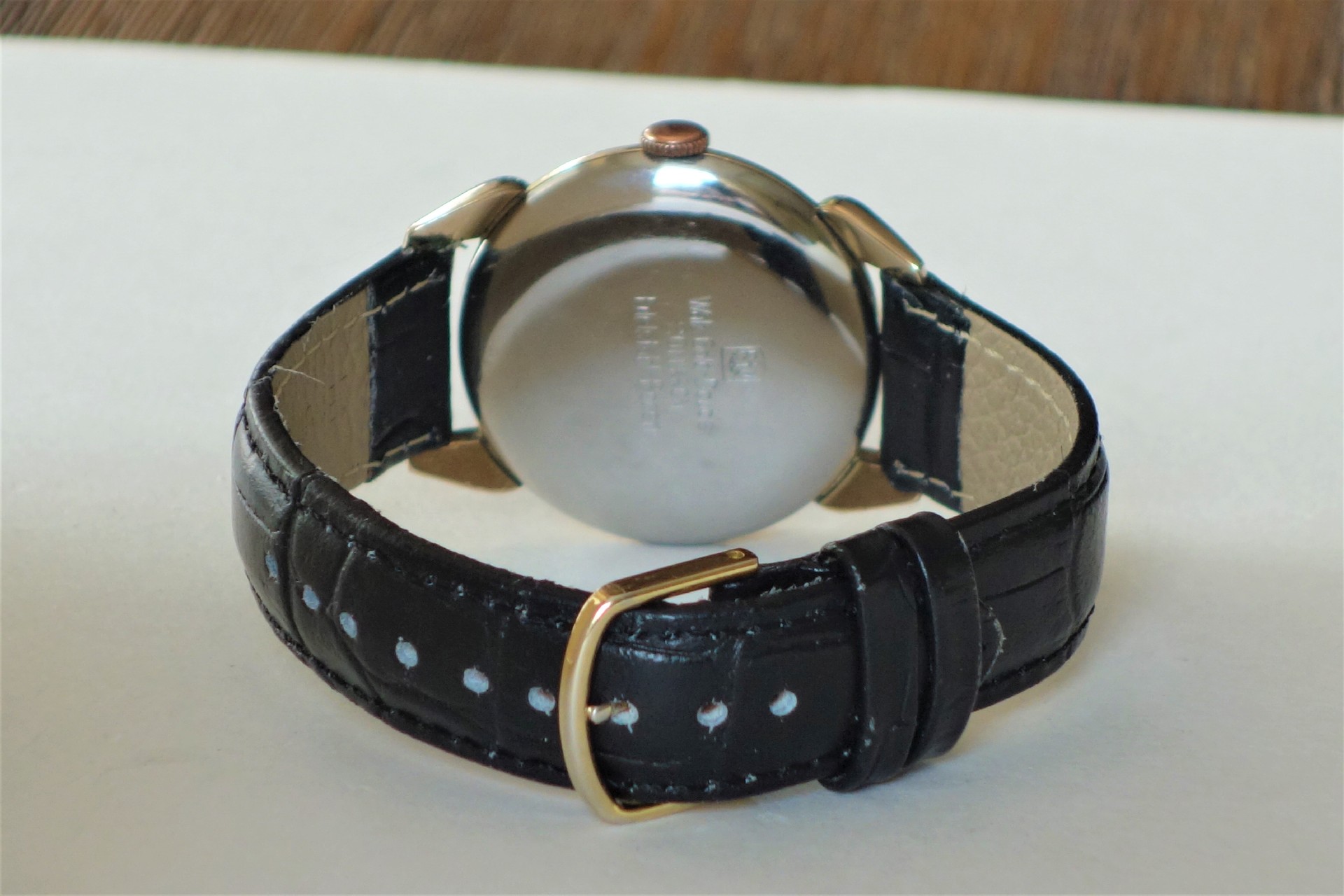 Armbanduhr mit schwarzem Armband und silberfarbener Rückseite.