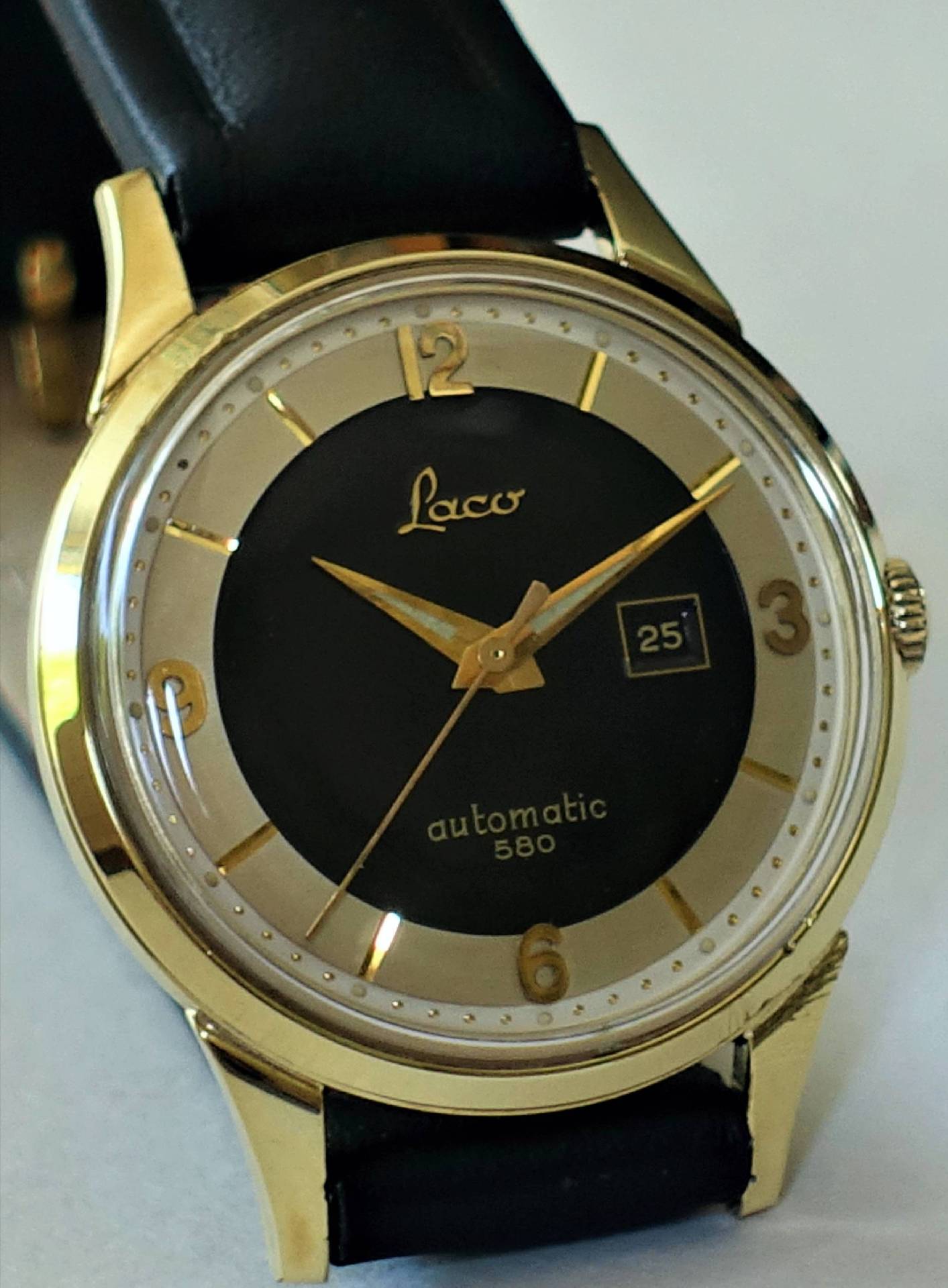 Schwarze und goldfarbene Armbanduhr mit Datumsanzeige und Lederarmband.