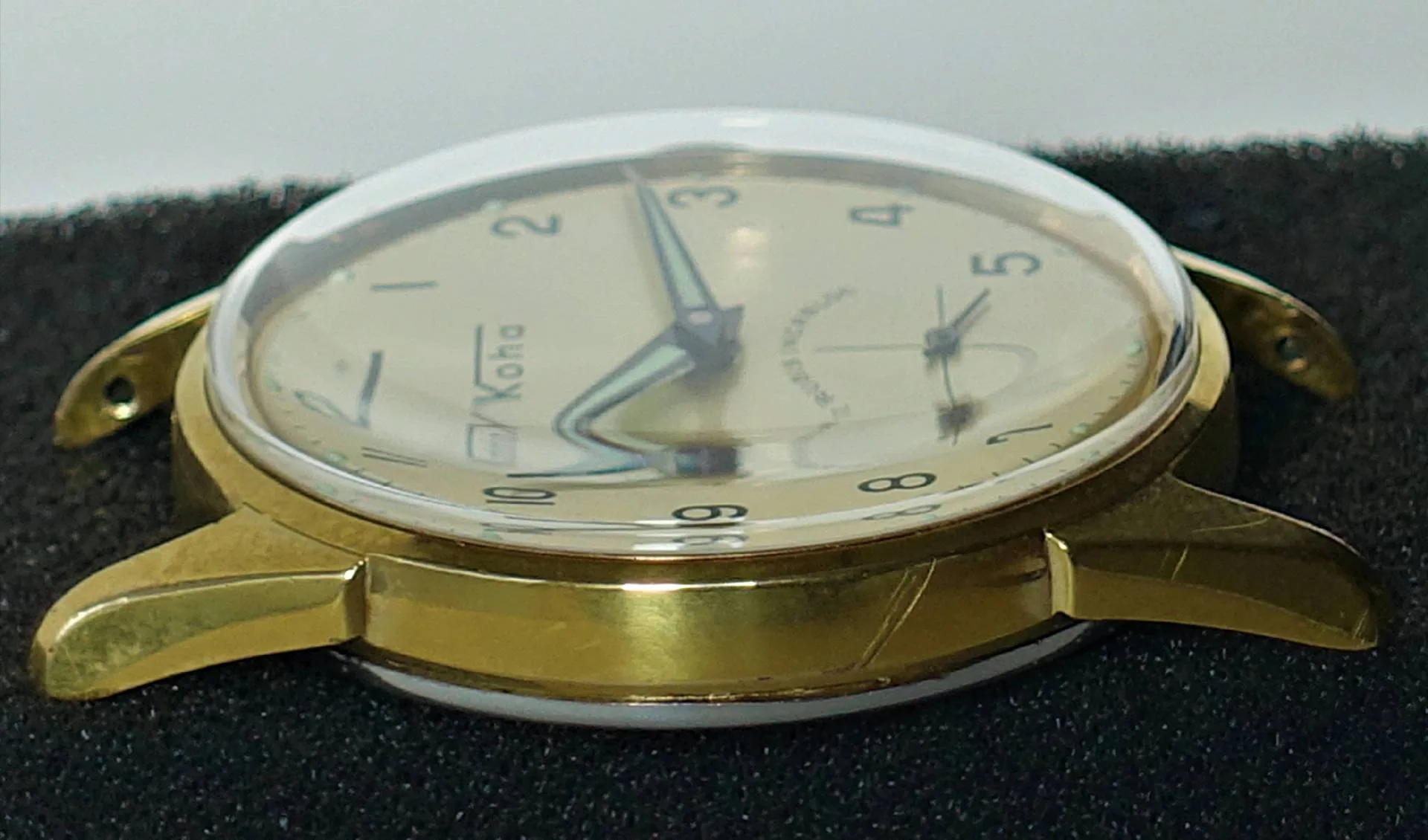 Goldfarbene Armbanduhr mit hellem Zifferblatt und schwarzen Zahlen.