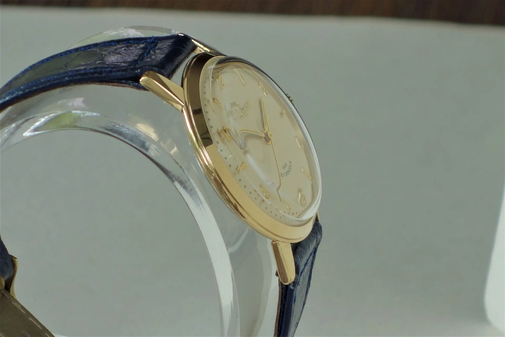 Analoge Armbanduhr mit goldfarbenem Gehäuse und blauem Armband.