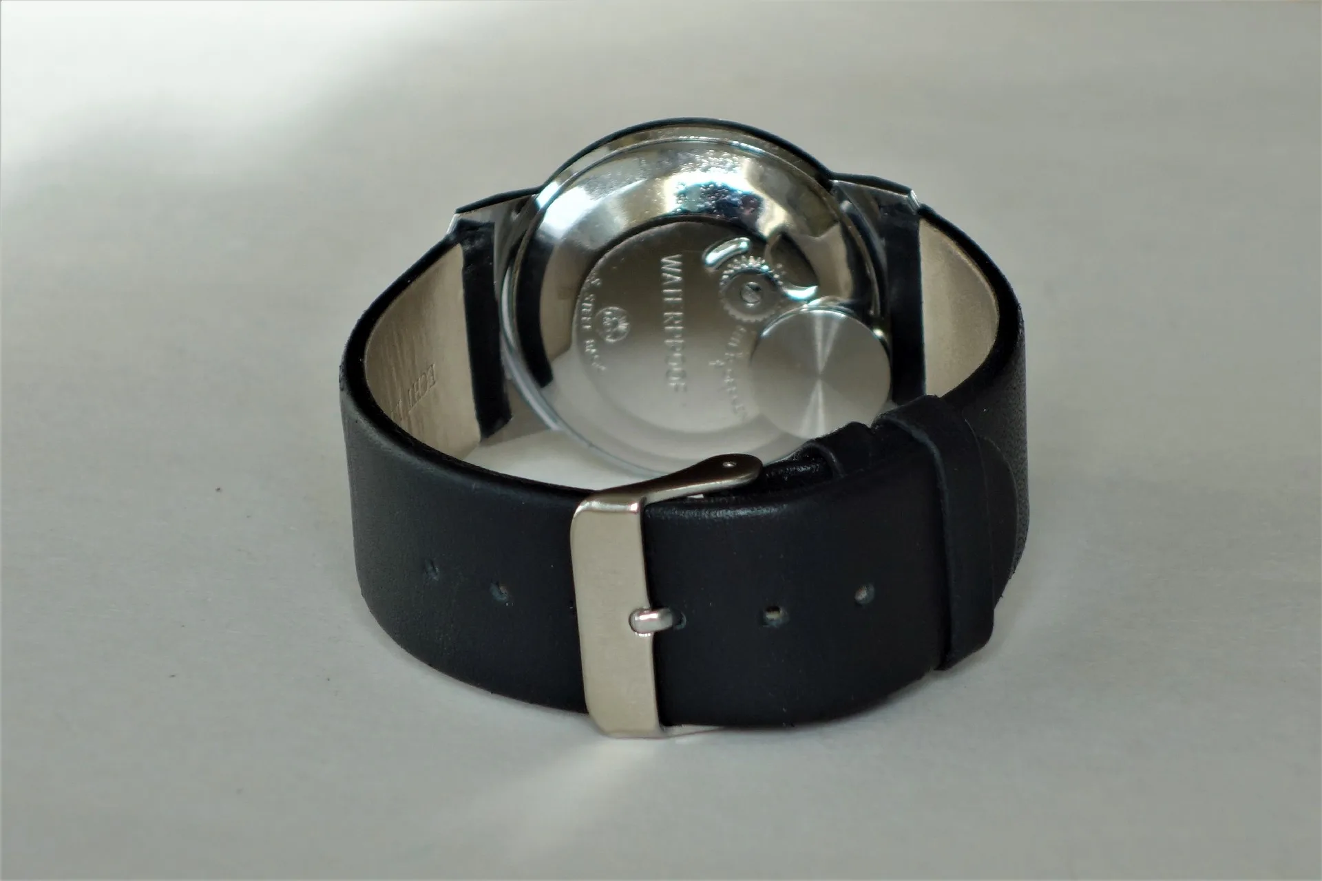 Armbanduhr mit Lederarmband Armbanduhr mit schwarzem Lederarmband und sichtbarem Metallboden.