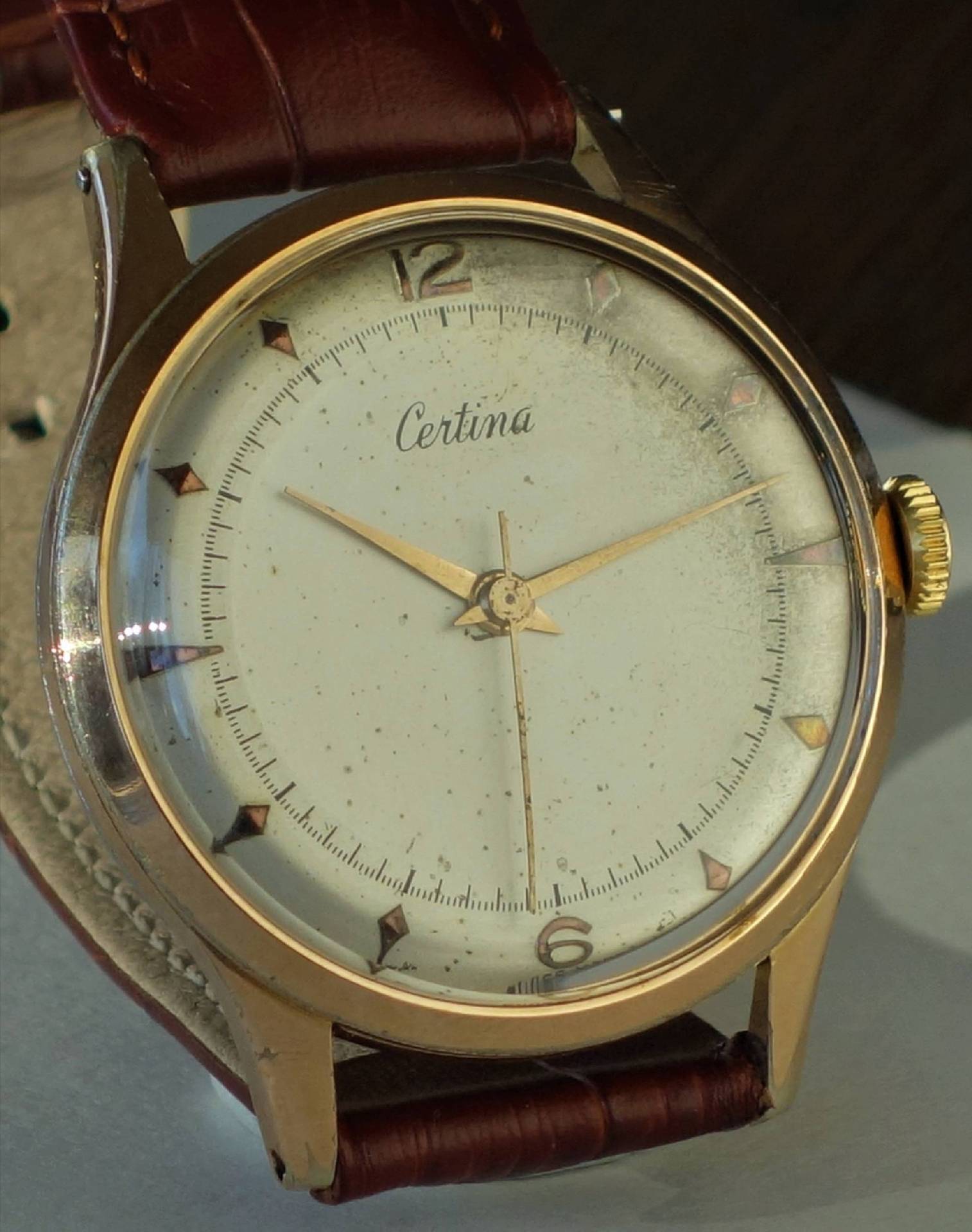 Goldfarbene Certina Armbanduhr mit hellem Zifferblatt und braunem Armband.