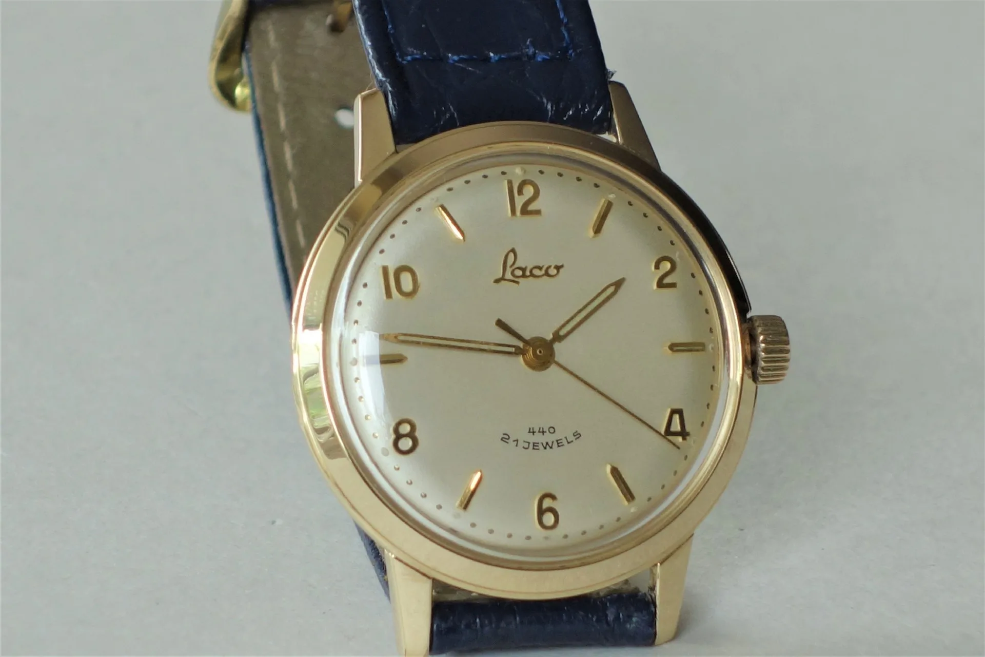 Armbanduhr goldfarben Goldfarbene Armbanduhr mit hellem Zifferblatt und blauem Armband.
