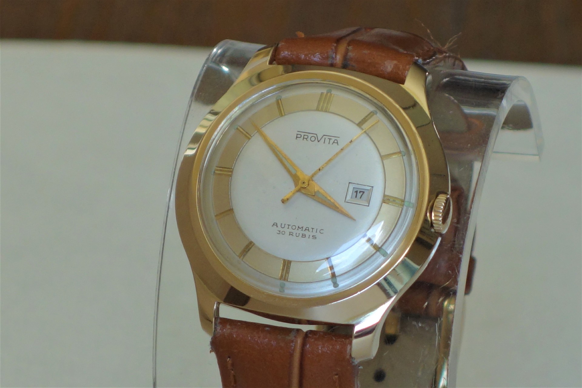 Goldfarbene Armbanduhr mit braunem Lederarmband und Datumsanzeige.