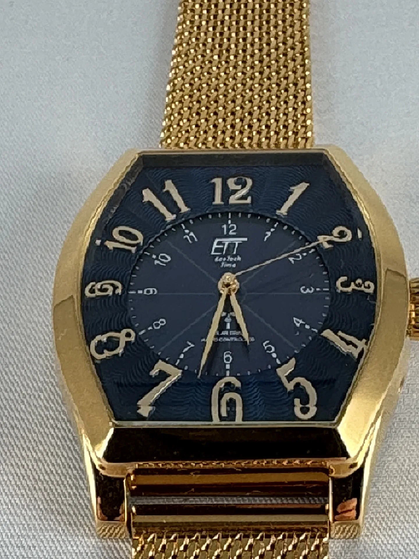 Goldfarbene Armbanduhr mit schwarzem Zifferblatt und goldfarbenem Milanaise-Edelstahlarmband.