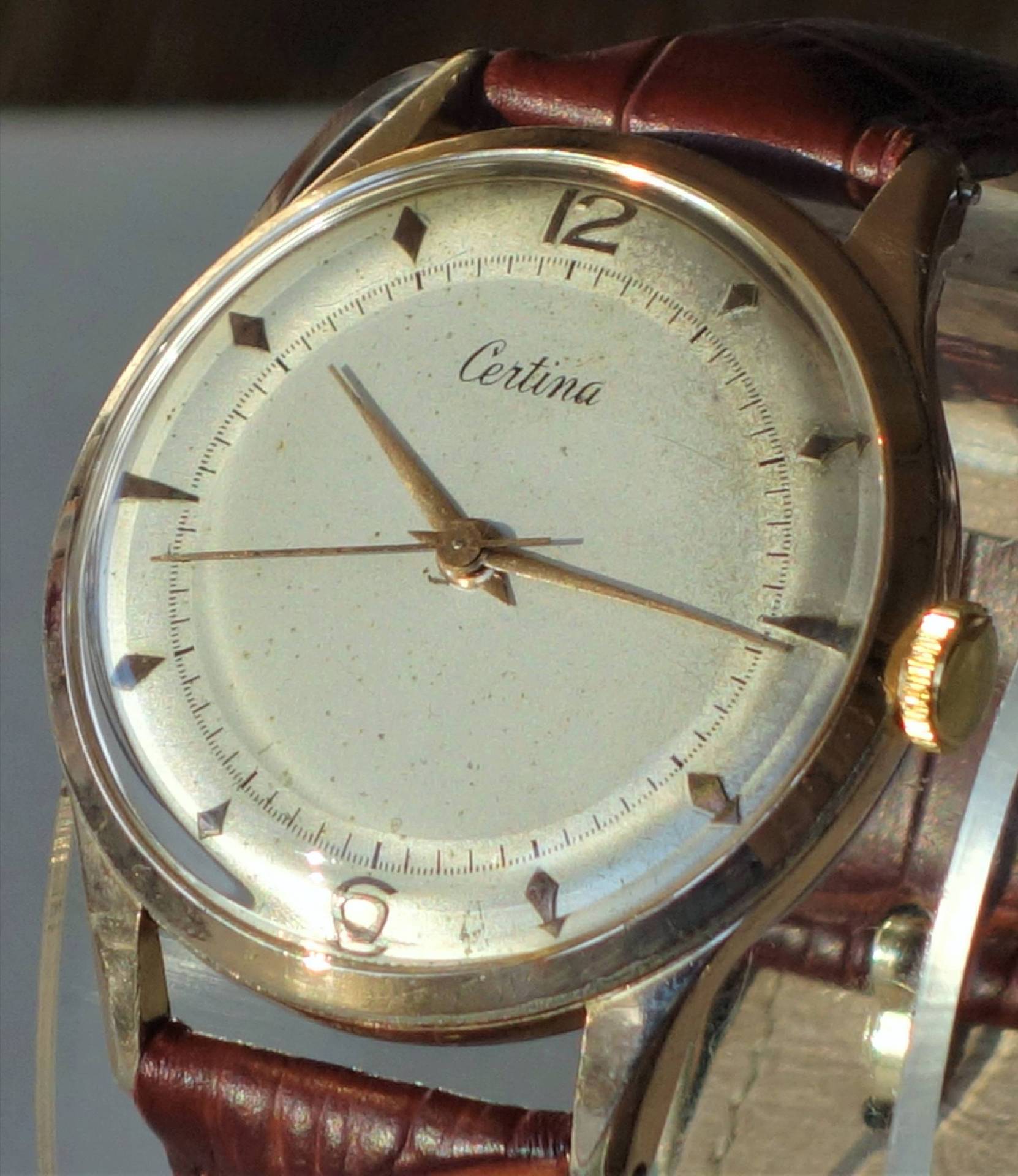 Goldfarbene Certina Armbanduhr mit hellem Zifferblatt und braunem Armband.