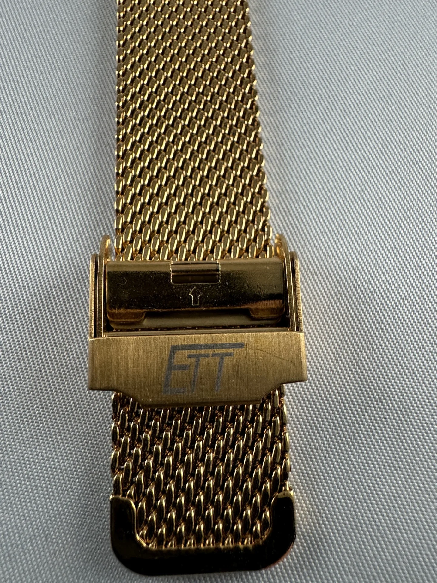 Goldfarbenes Milanaise-Uhrenarmband mit Faltschließe und ETT Gravur.