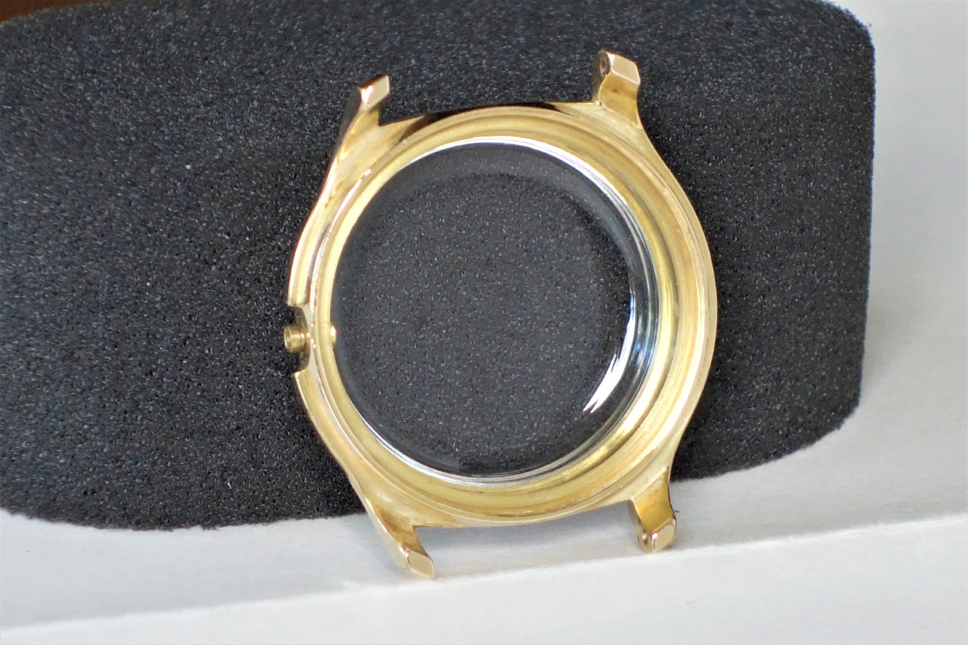 Rundes Uhrgehäuse in goldfarbener Optik mit transparentem Uhrglas.