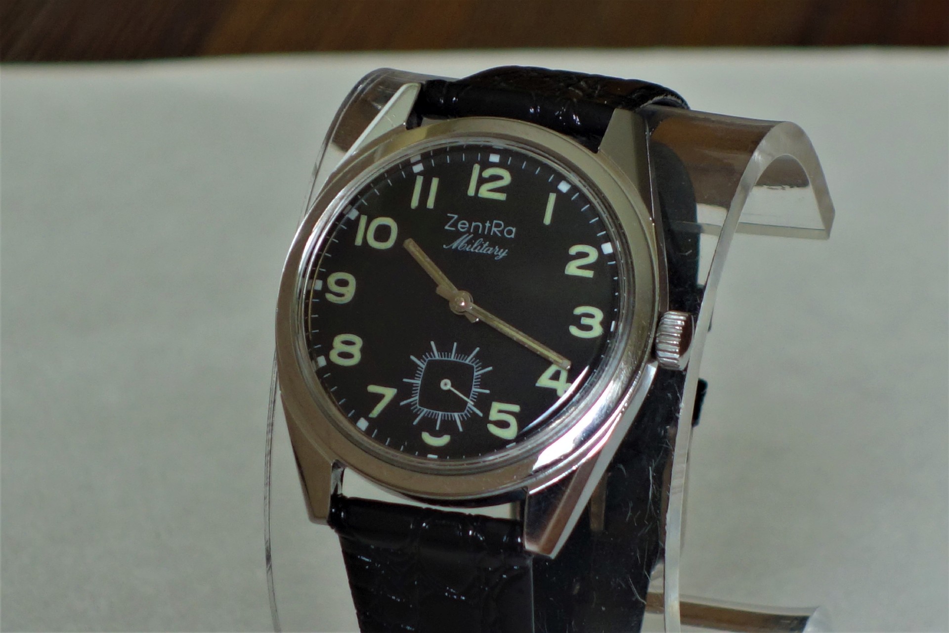 Schwarze Armbanduhr mit hellem Zifferblatt und schwarzem Armband.