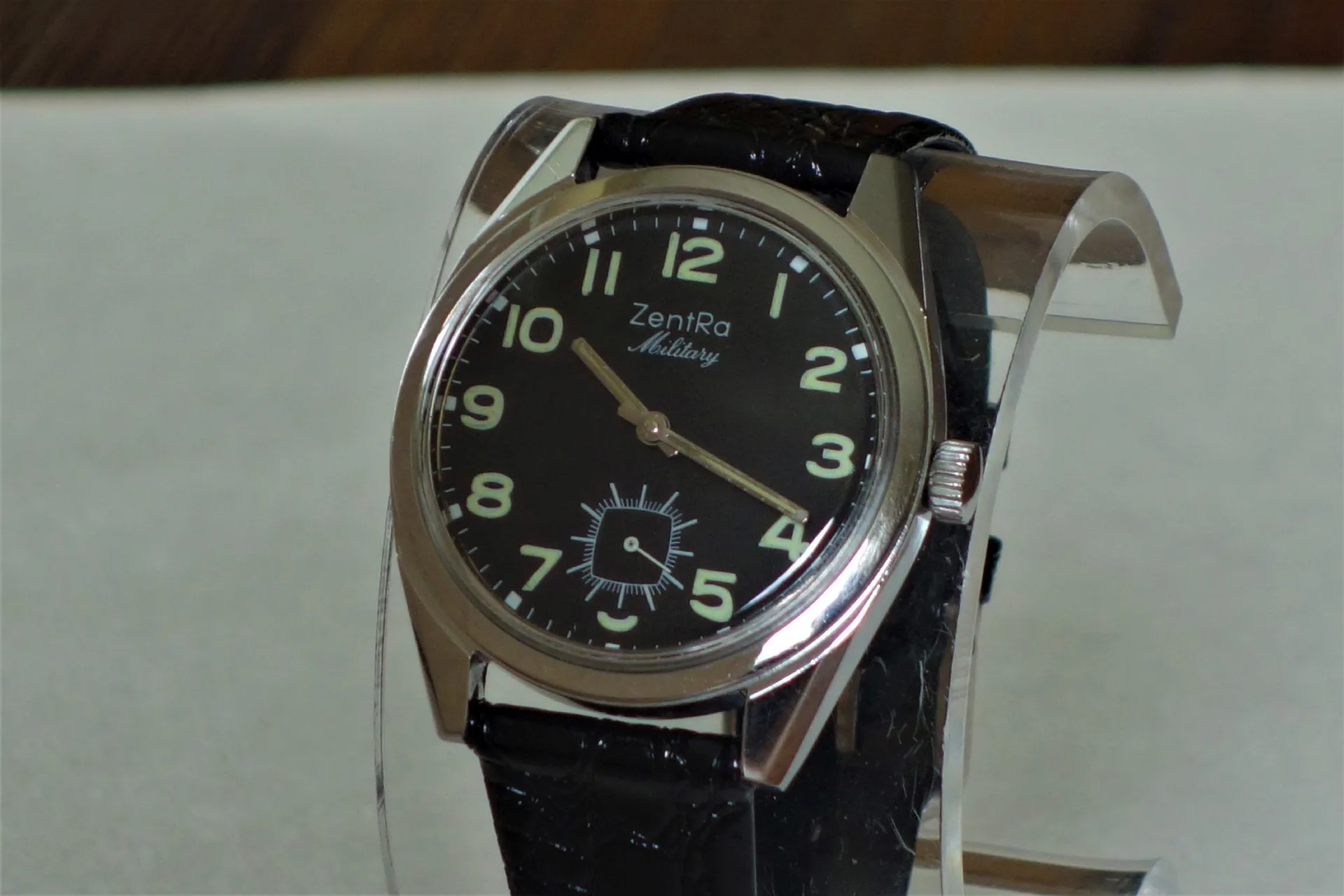 Schwarze Armbanduhr mit hellem Zifferblatt und schwarzem Armband.