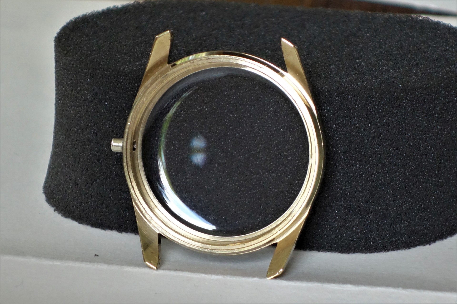Goldfarbenes Uhrgehäuse mit montiertem Uhrglas, ohne Uhrwerk und Armband.
