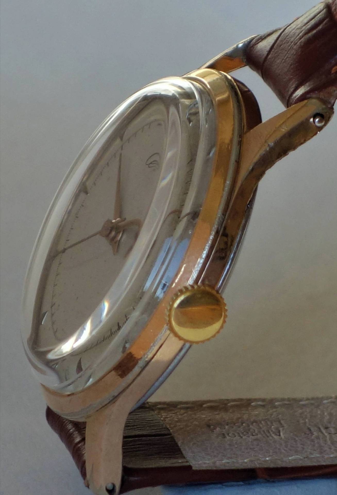 Analoge Armbanduhr mit goldfarbenem Gehäuse und braunem Lederarmband.