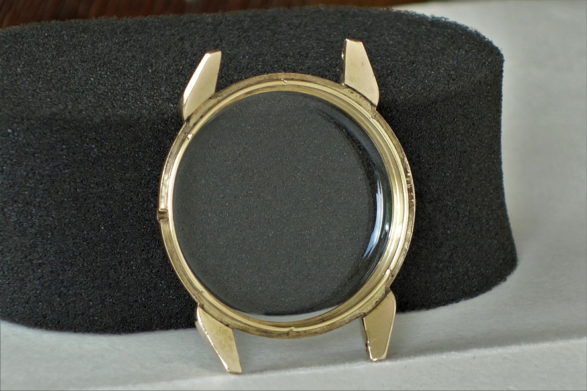Rundes Uhrgehäuse in goldfarbener Optik mit transparentem Glas.