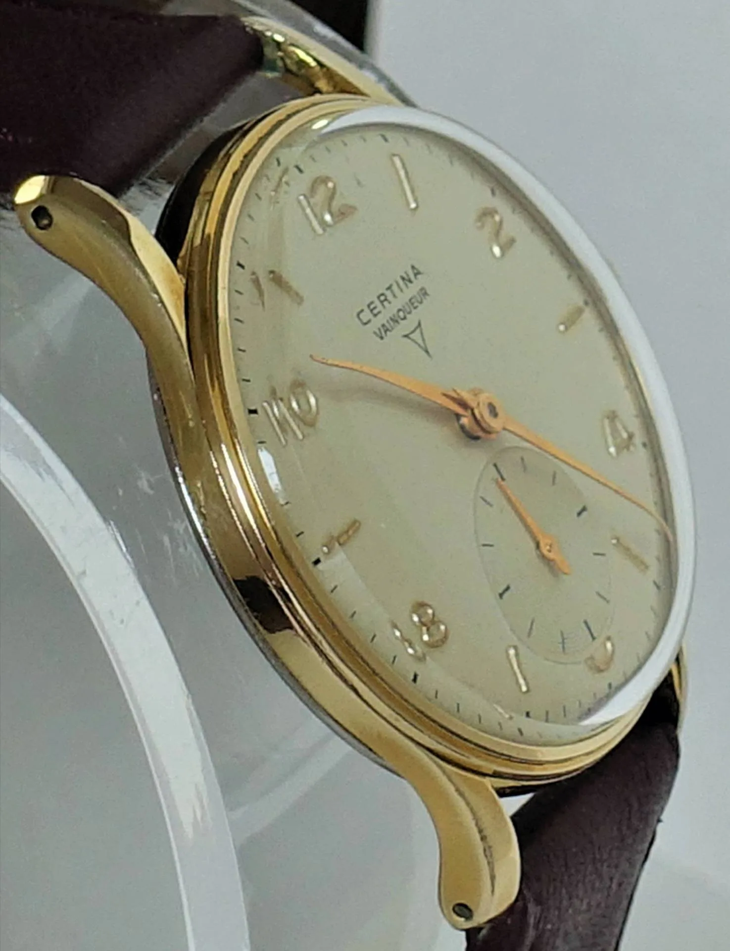 Certina Armbanduhr goldfarben Goldfarbene Armbanduhr mit hellem Zifferblatt und braunem Armband.
