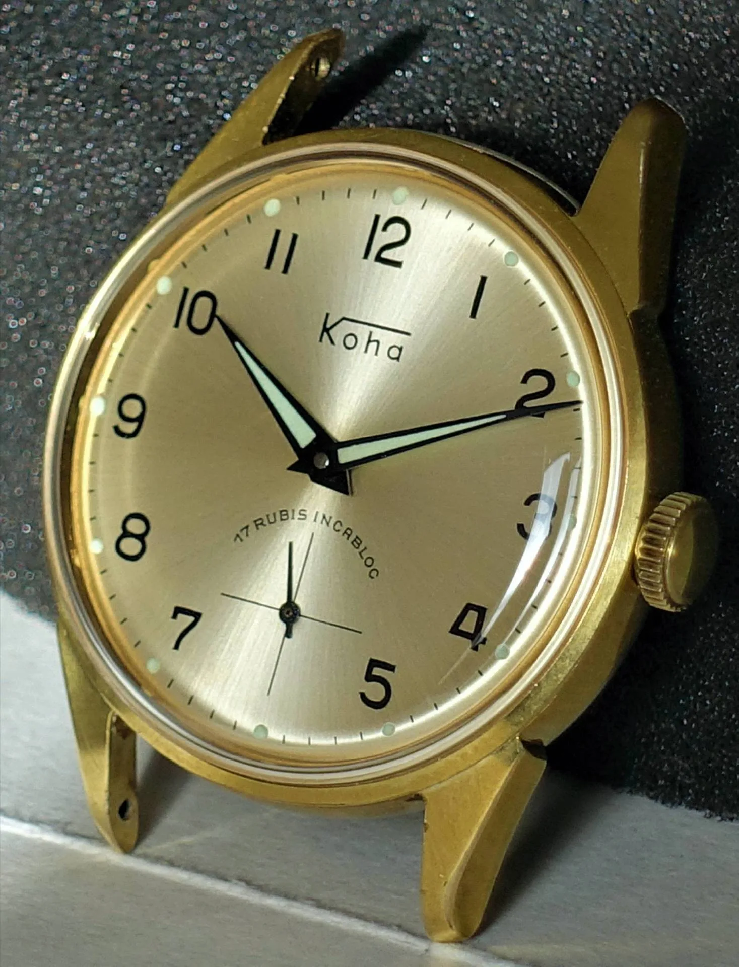 Goldfarbene Armbanduhr mit hellem Zifferblatt und schwarzen Zahlen.