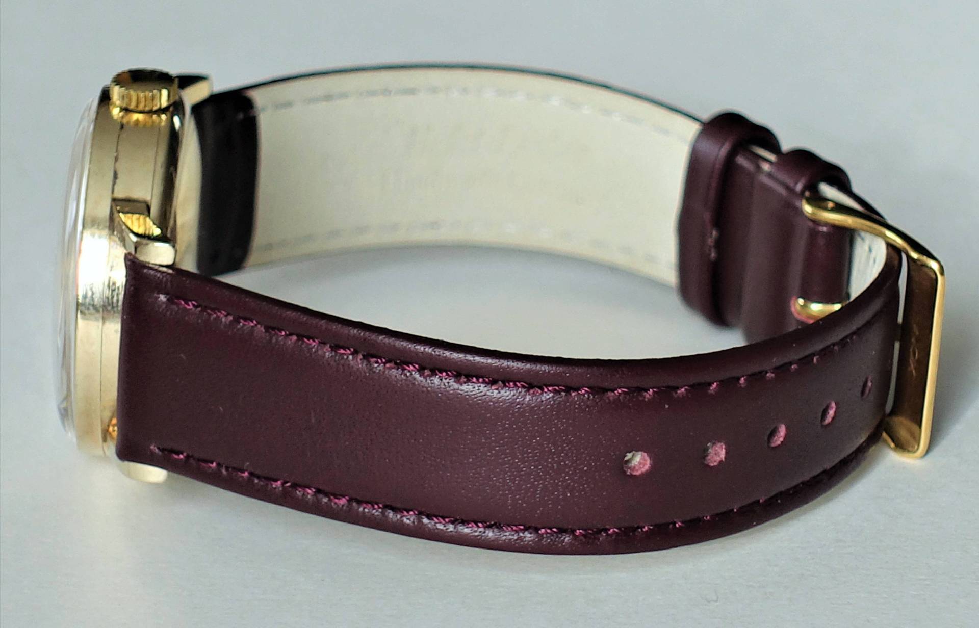 Detailansicht einer eleganten Armbanduhr mit burgunderfarbenem Lederarmband