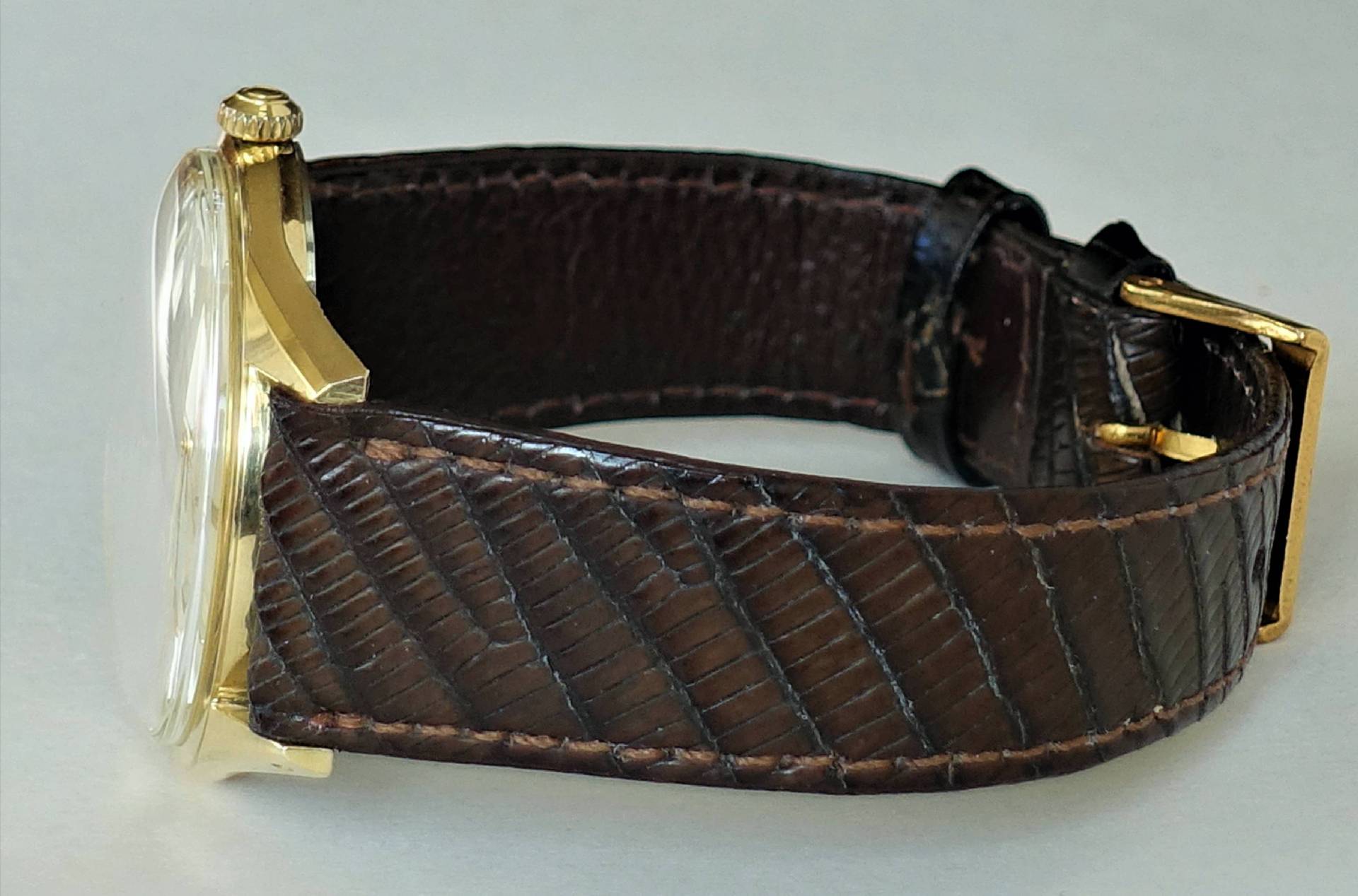 Armbanduhr mit braunem Armband und goldfarbenem Gehäuse.