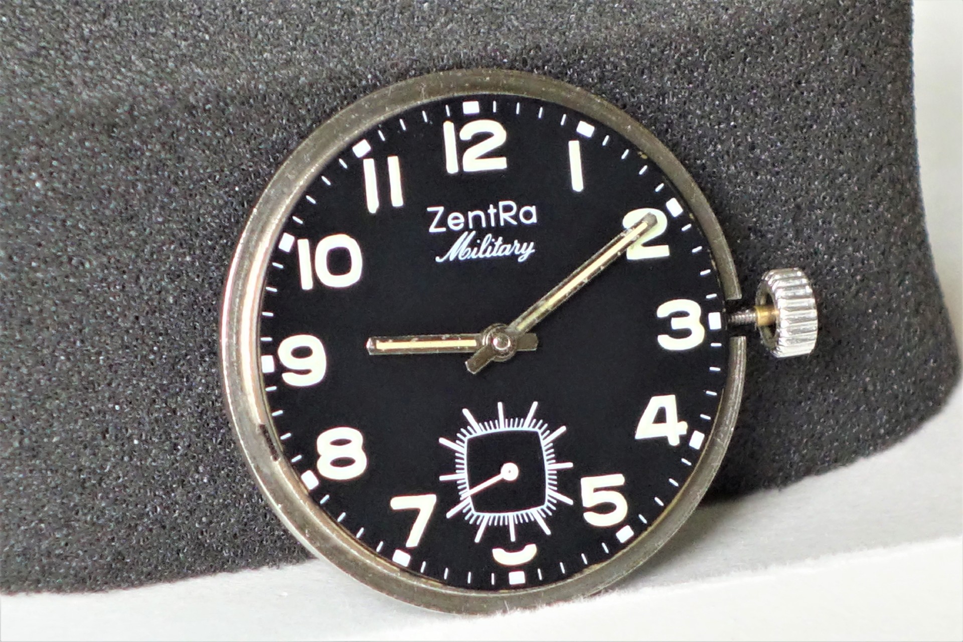 Schwarzes Uhrwerk mit weißer ZentRa Military Beschriftung und silberner Krone.