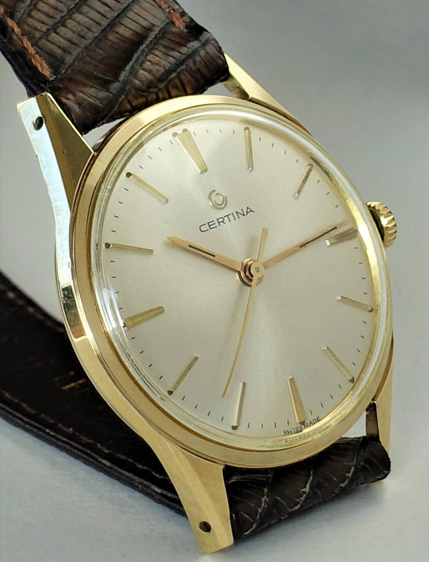 Goldfarbene Certina Armbanduhr mit hellem Zifferblatt und braunem Armband.