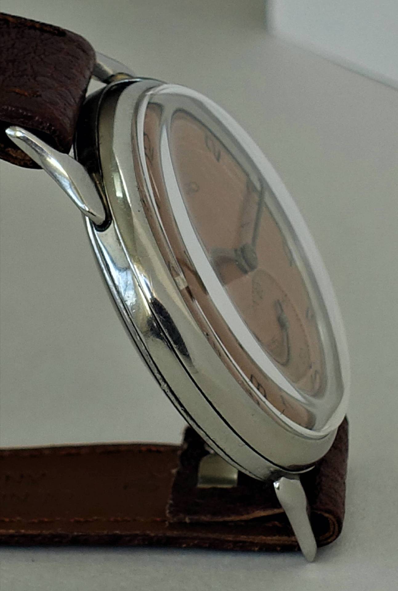 Silberfarbene Armbanduhr mit braunem Armband und hellem Zifferblatt.