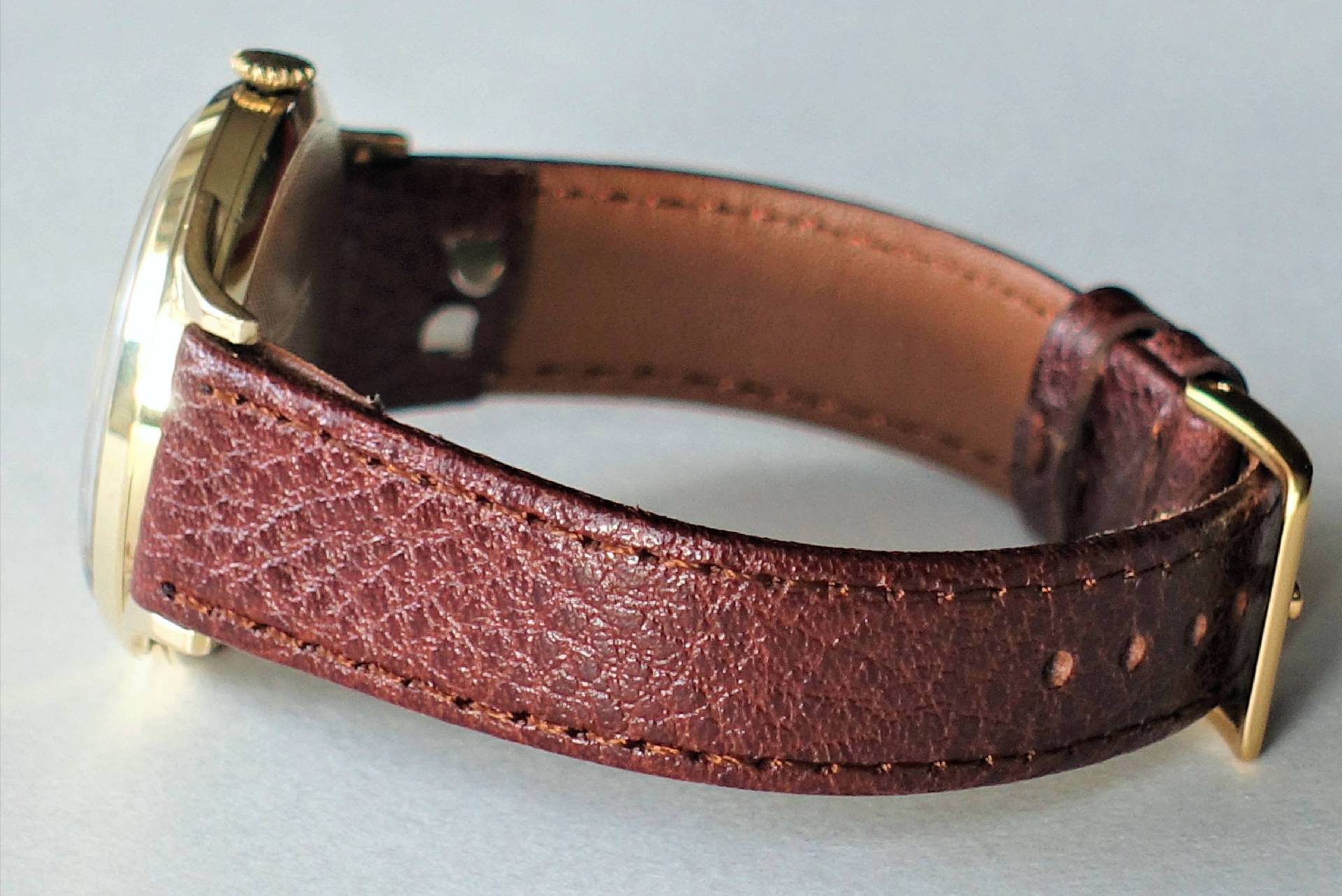Armbanduhr mit braunem Lederarmband und goldfarbenem Gehäuse.