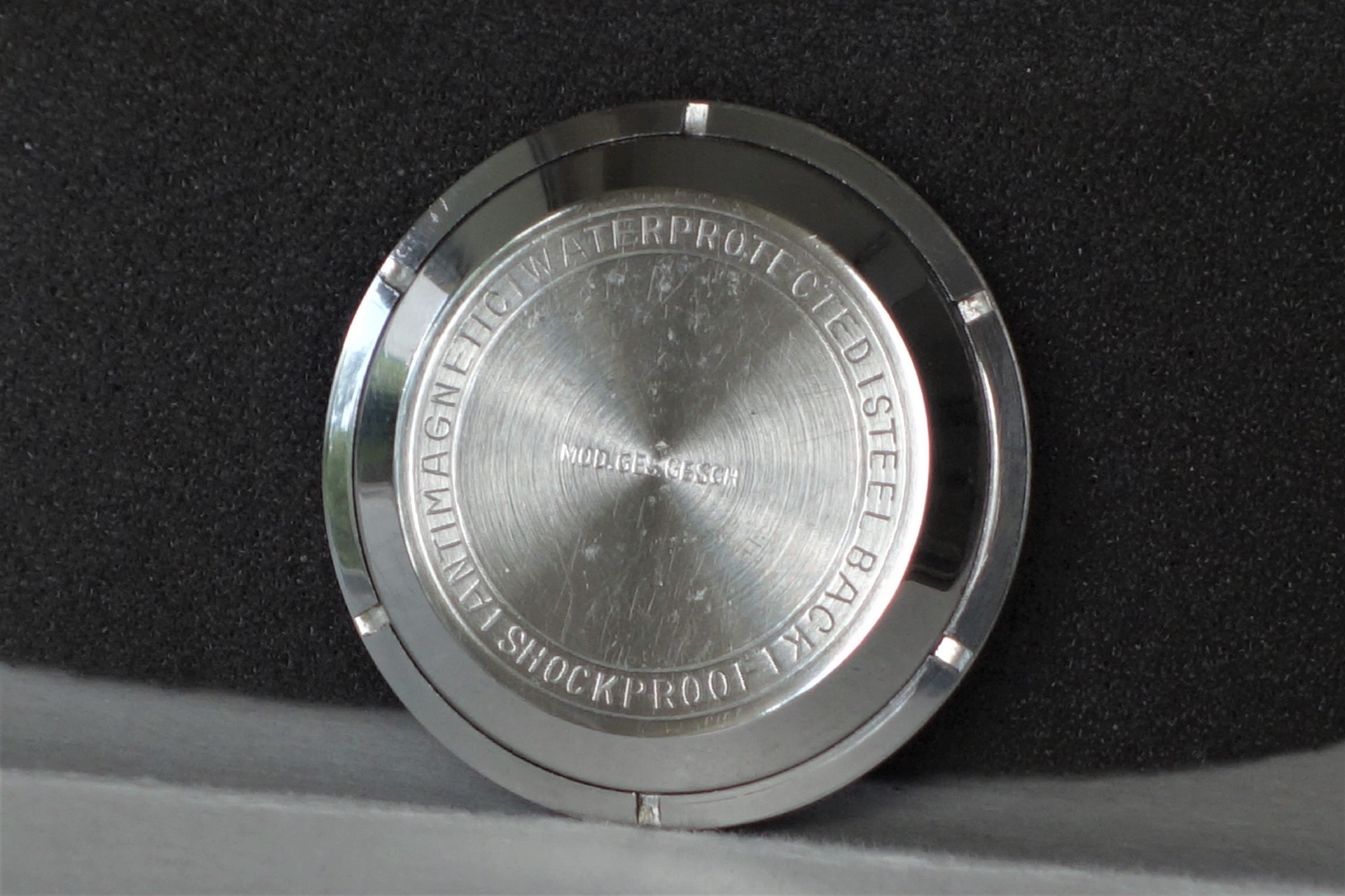 Runder silberfarbener Uhrenboden mit Gravur auf der Rückseite.