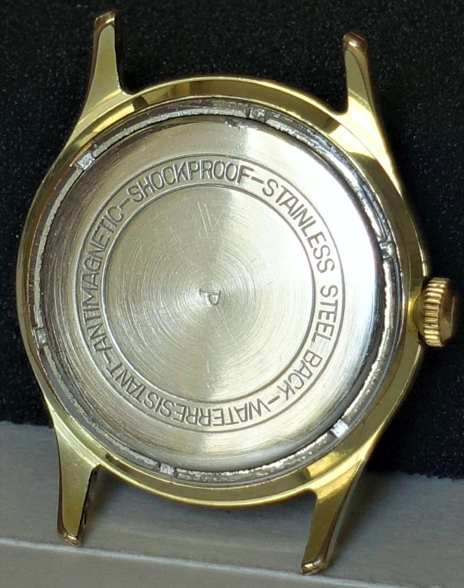 Rundes Uhrgehäuse in goldfarbener Ausführung mit silberfarbener Rückseite.