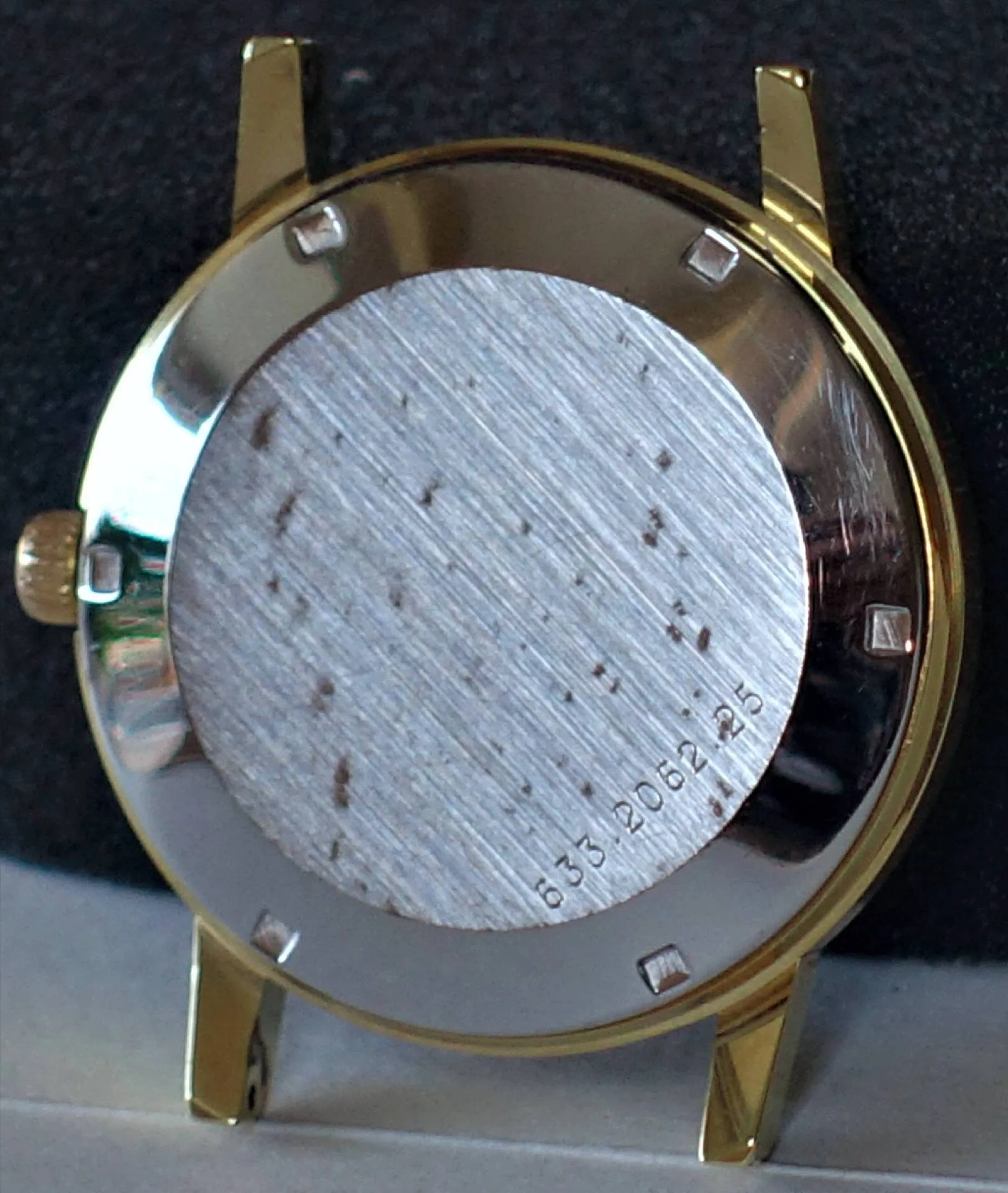 Gehäuse Rückseite goldfarben Rückseite eines goldfarbenen Uhrgehäuses mit silberfarbigem Boden und seitlicher Krone.