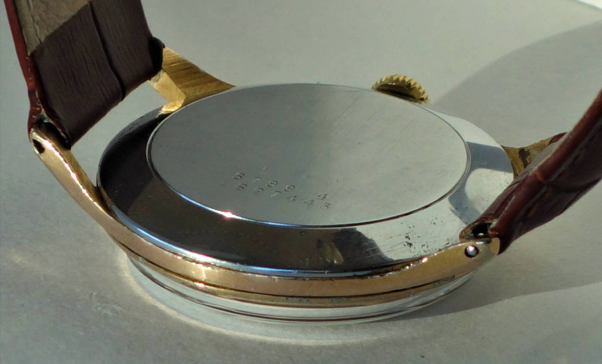 Silberfarbener Uhrenboden mit Gravur an einer Armbanduhr mit braunem Band.