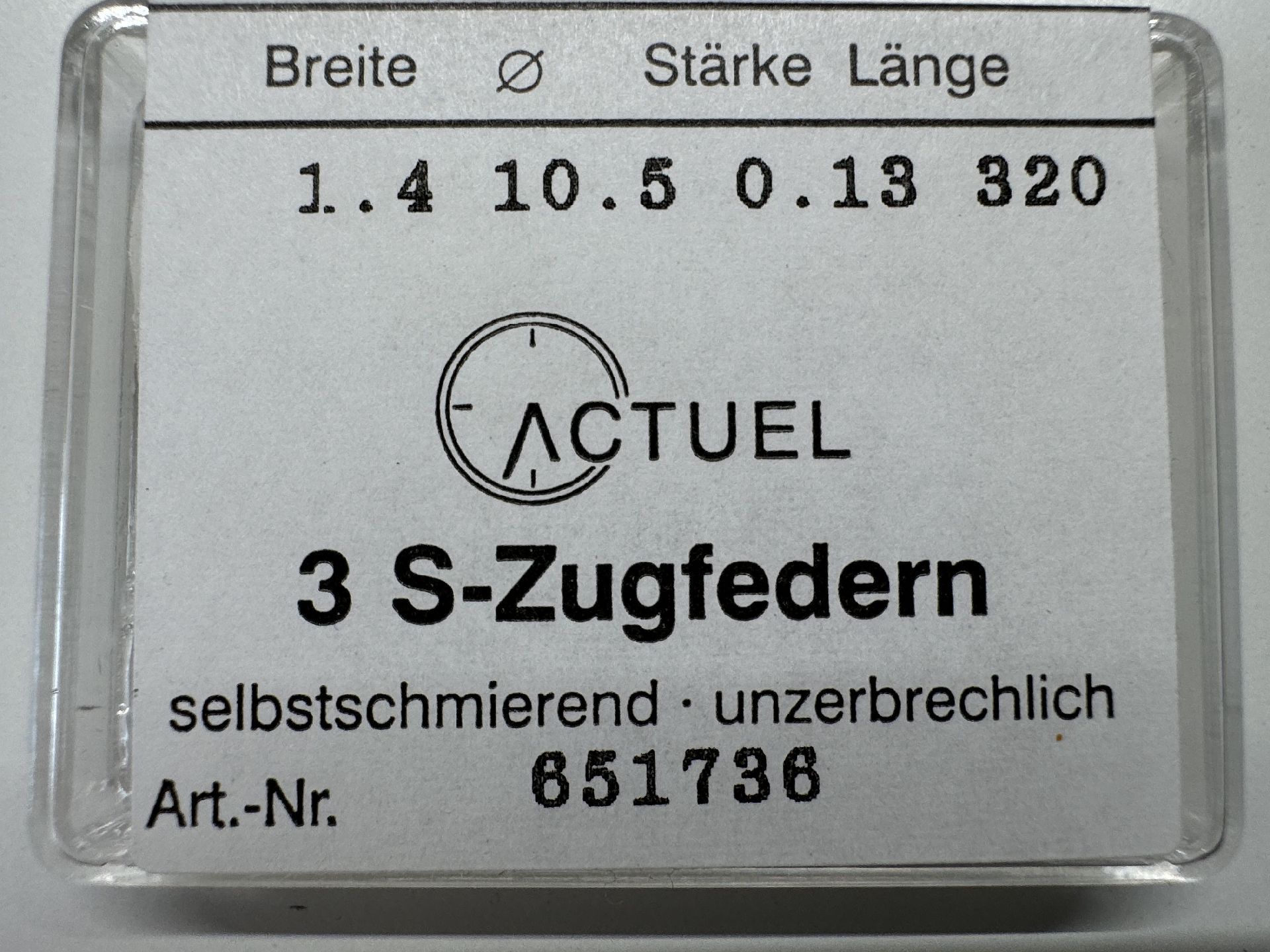 Drei silberfarbene Zugfedern für Uhrwerke in transparenter Verpackung.