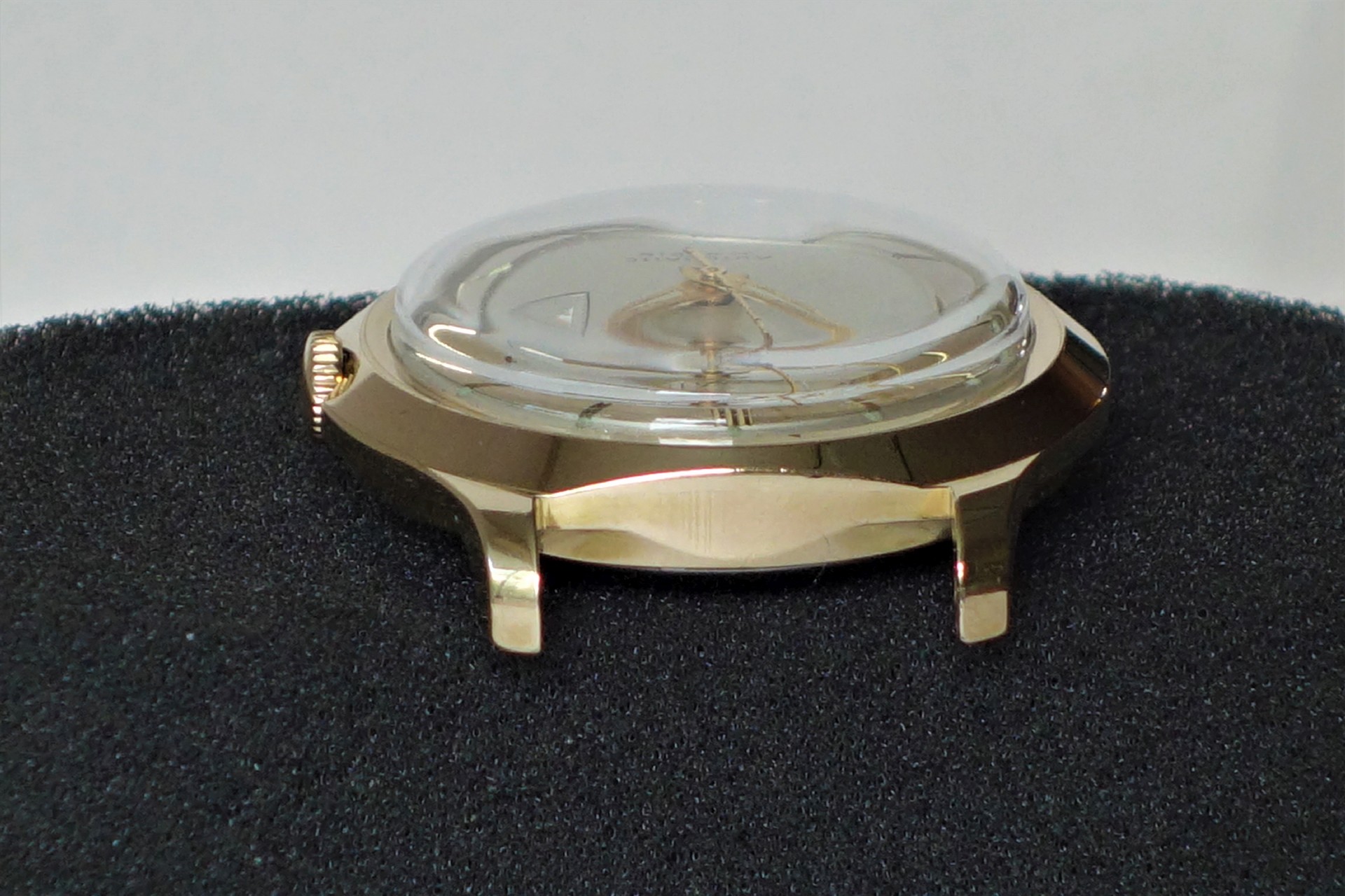 Goldfarbenes Uhrgehäuse mit gewölbtem Glas und sichtbarer Krone.