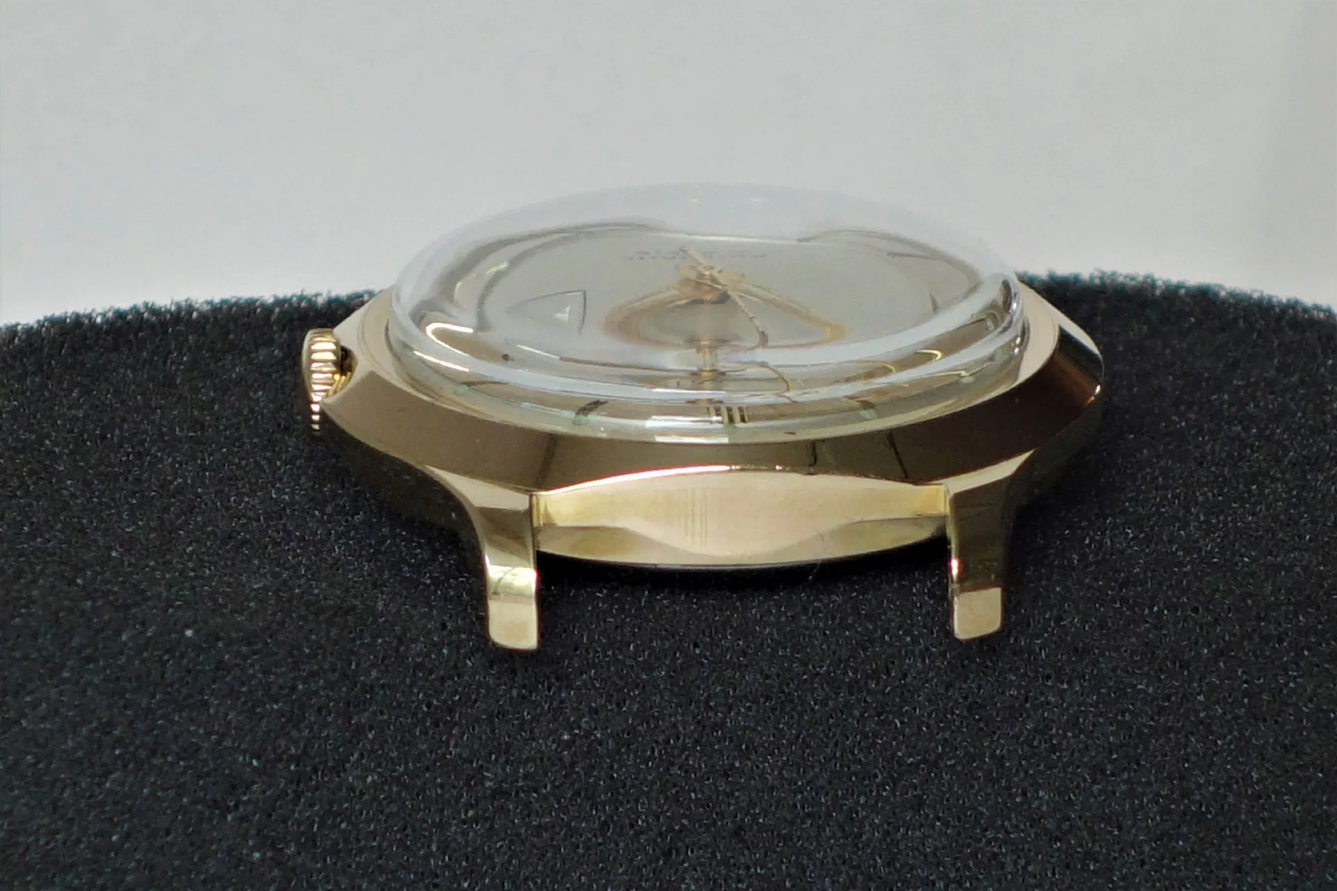 Goldfarbenes Uhrgehäuse mit gewölbtem Glas und sichtbarer Krone.