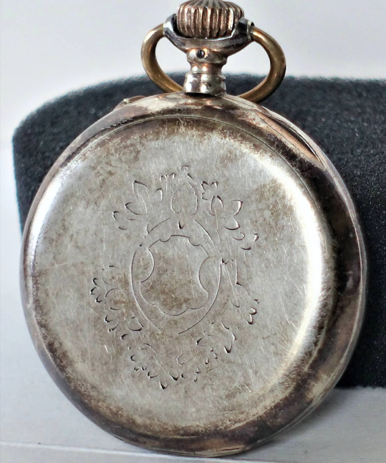 Taschenuhr silberfarben Rückseite einer silberfarbenen Taschenuhr mit Gravur und Aufzugsöse.
