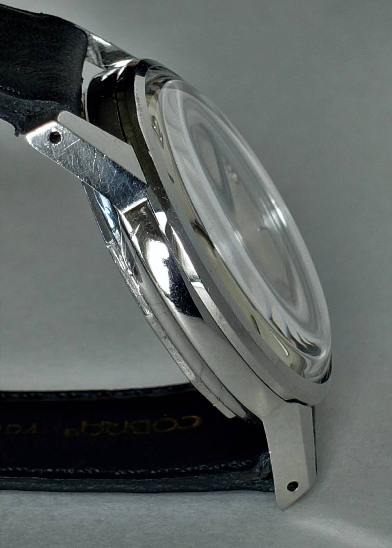 Detailaufnahme einer eleganten Armbanduhr mit silbernem Gehäuse und schwarzem Lederarmband.