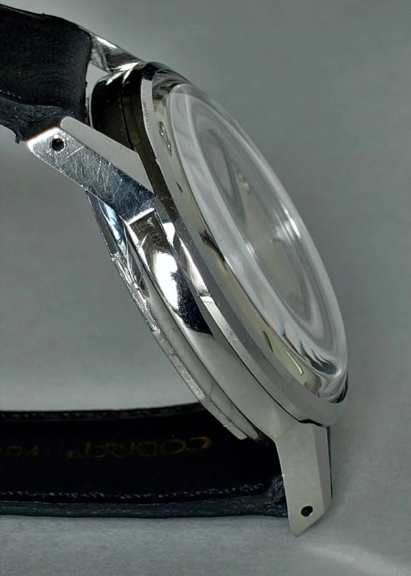 Detailaufnahme einer eleganten Armbanduhr mit silbernem Gehäuse und schwarzem Lederarmband.